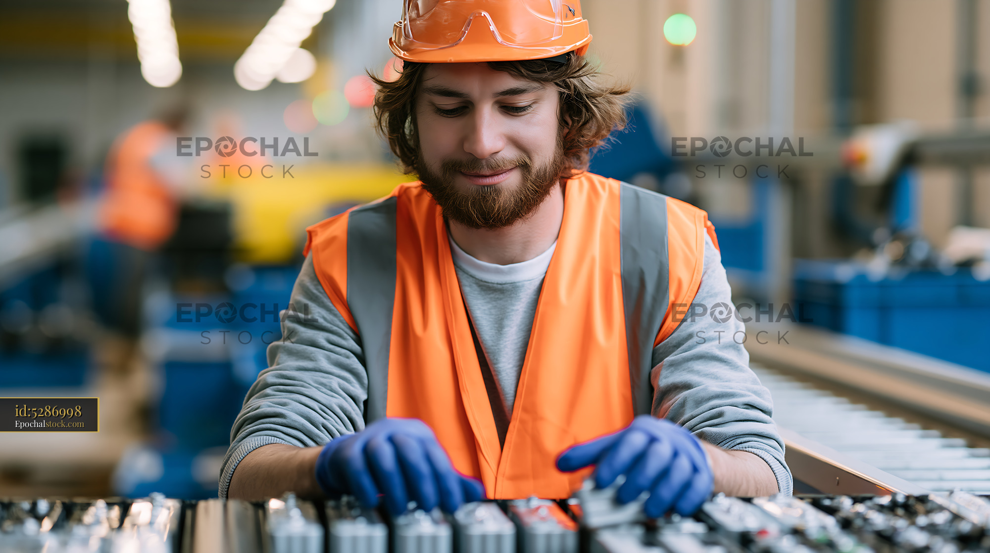 Watermarked full-resolution preview of Worker in safety gear assembling components in a factory