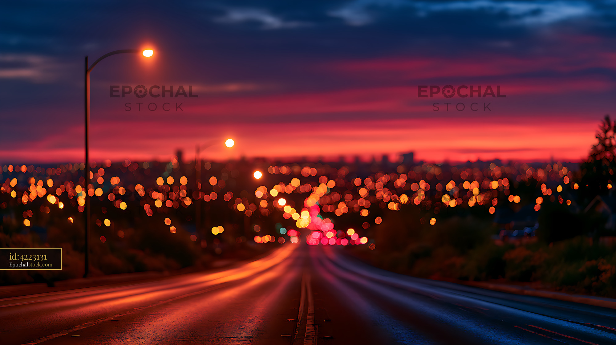 Watermarked full-resolution preview of Defocused urban road glowing beneath a colorful sunset