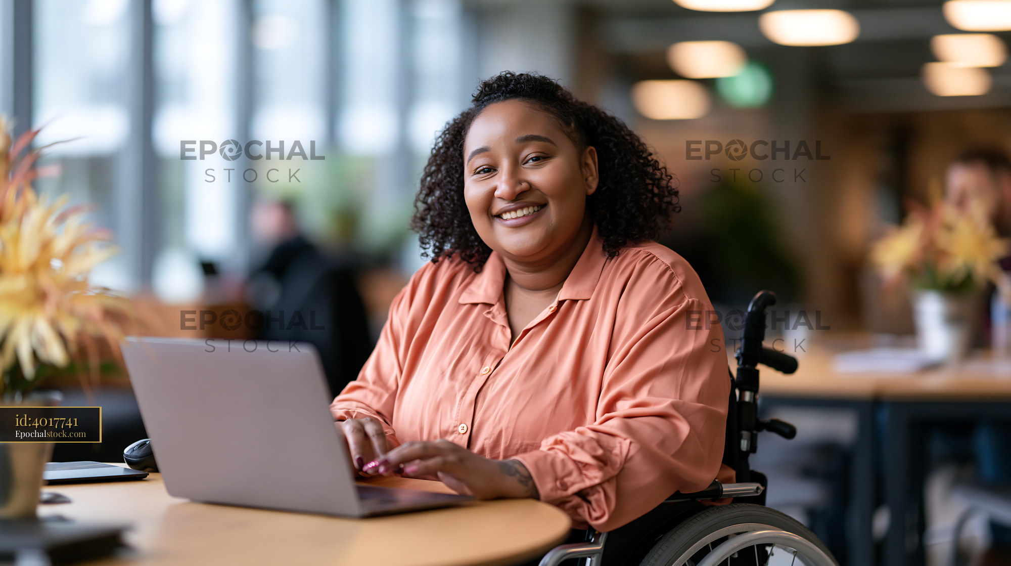 Watermarked full-resolution preview of Woman in wheelchair working on laptop in modern office setting