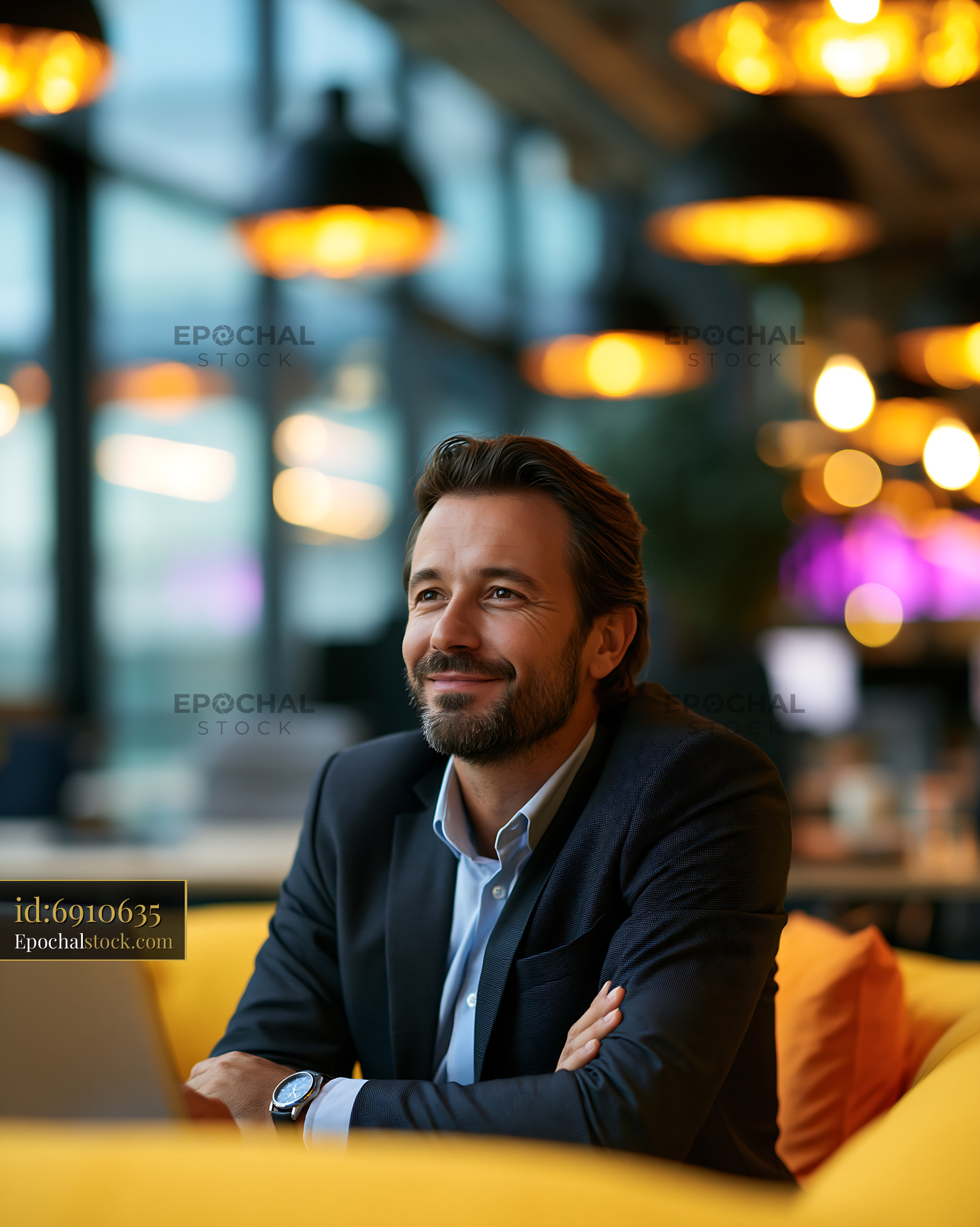 Watermarked full-resolution preview of Man sitting in a modern workspace with a laptop and warm lighting