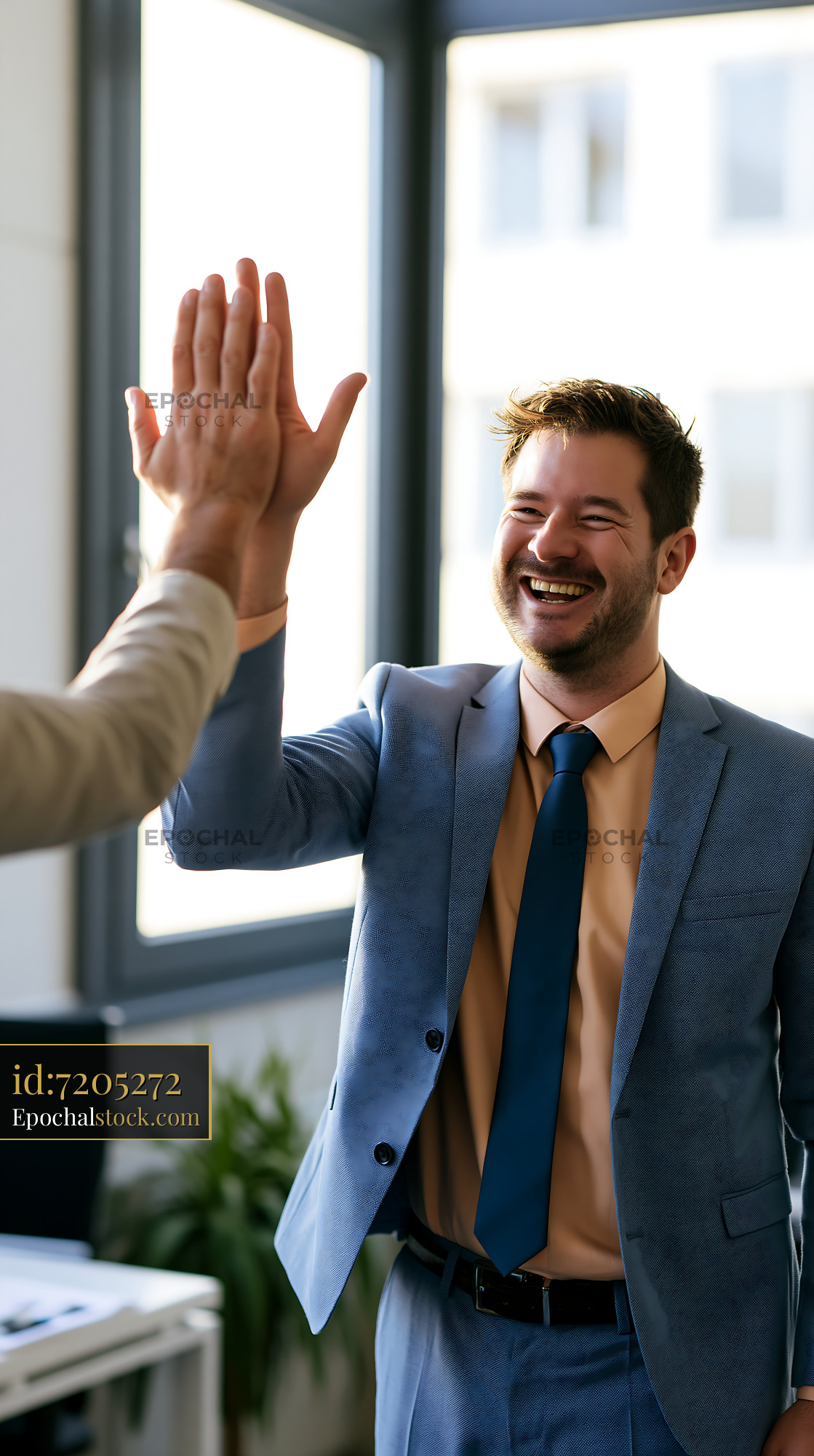 Watermarked full-resolution preview of Business partners celebrate success with a high-five in an office