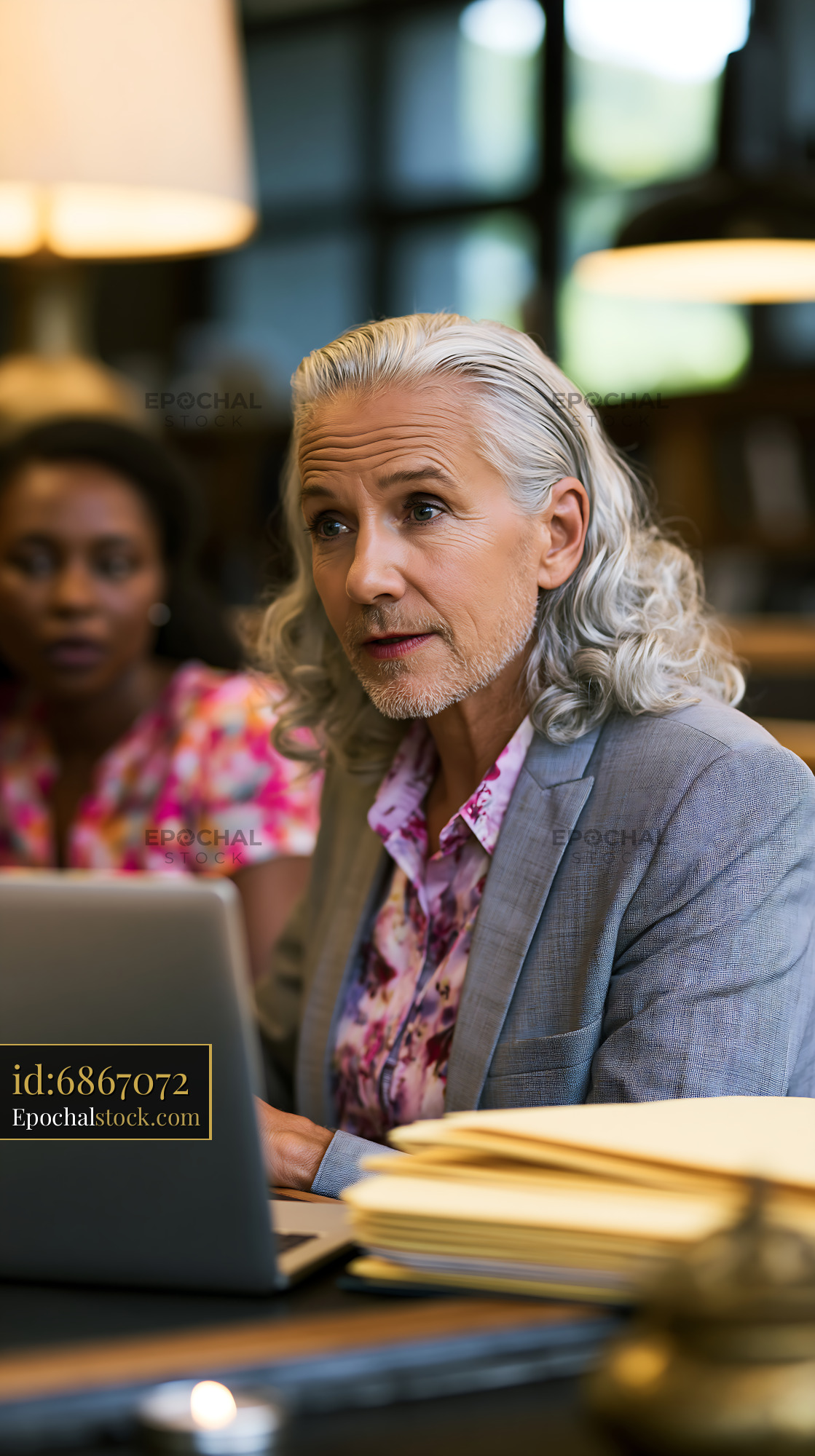 Watermarked full-resolution preview of Business meeting in a library with two professionals discussing plans