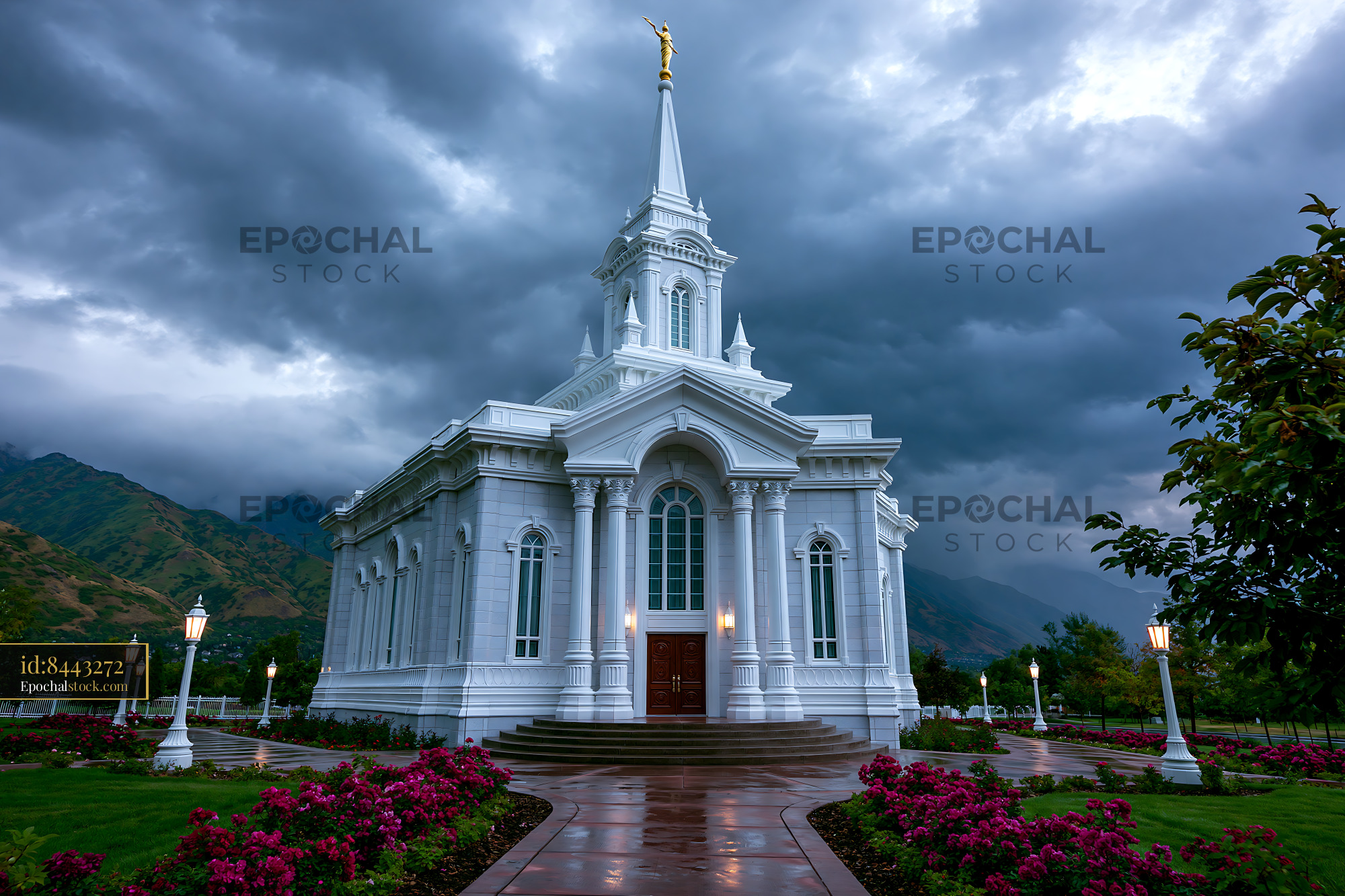 Watermarked full-resolution preview of Church building surrounded by flowers and mountains under cloudy sky
