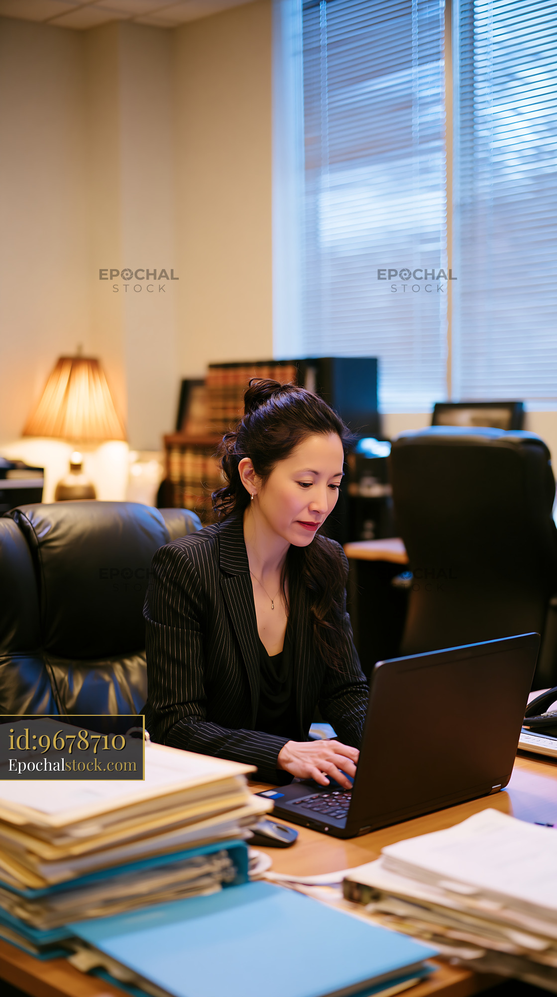 Watermarked full-resolution preview of Businesswoman working at desk with laptop in office