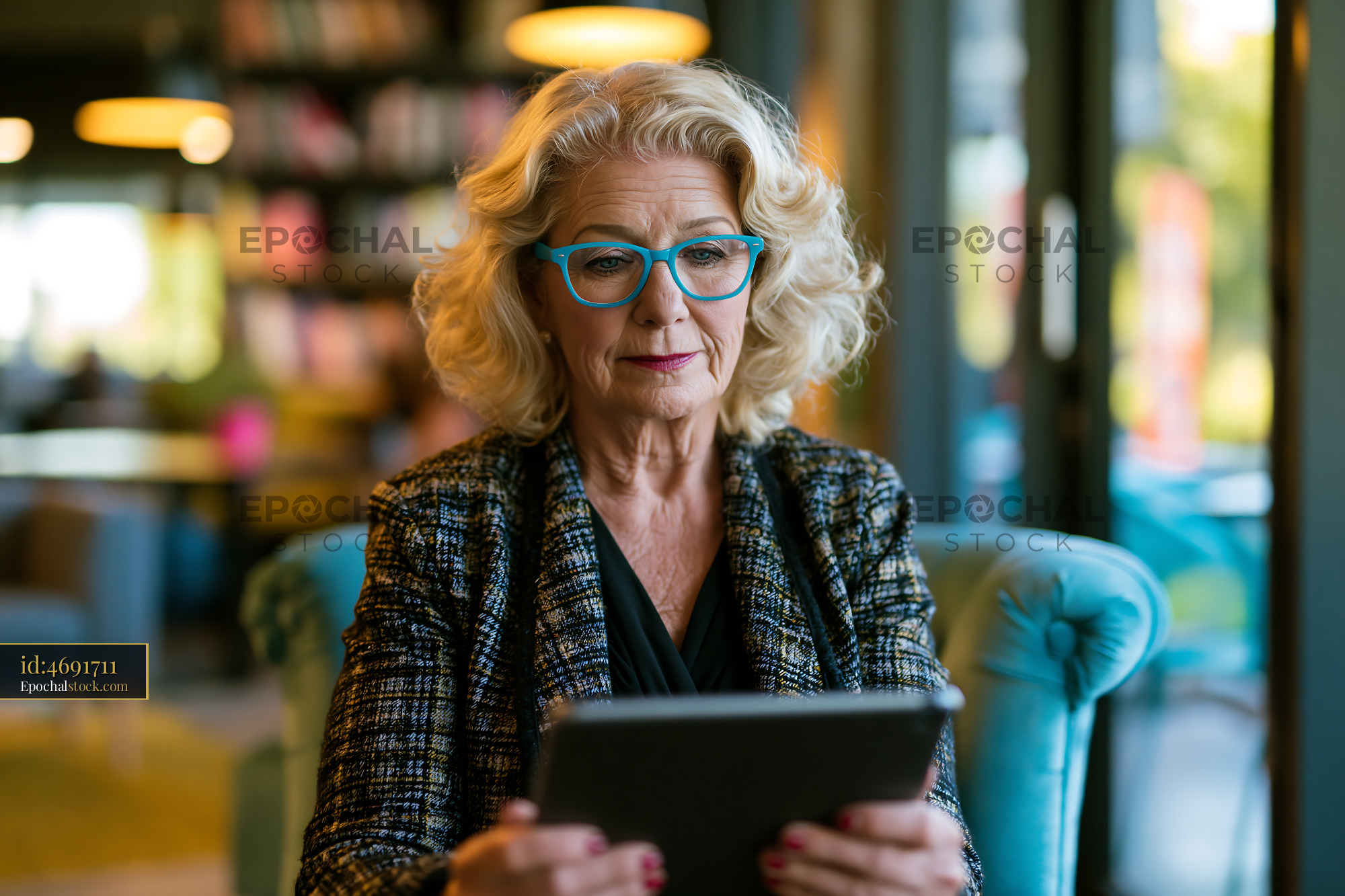 Watermarked full-resolution preview of Woman sitting in a cafe using a tablet with a relaxed expression