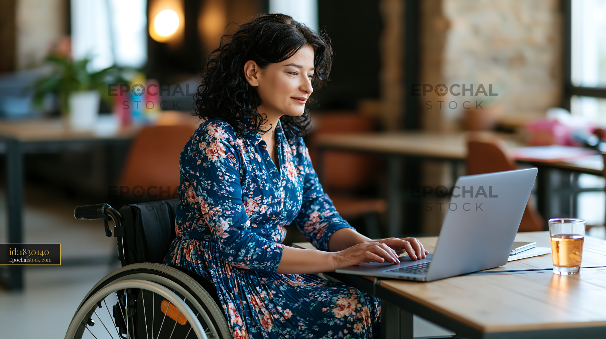 Watermarked full-resolution preview of Woman in wheelchair working on laptop at cafe