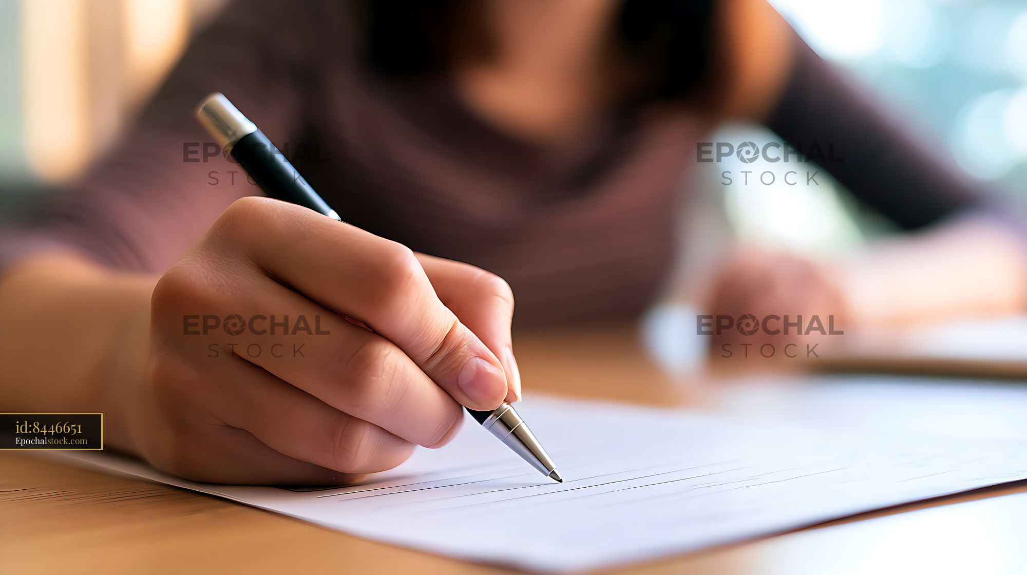 Watermarked full-resolution preview of Hand writing on paper with a pen at a desk