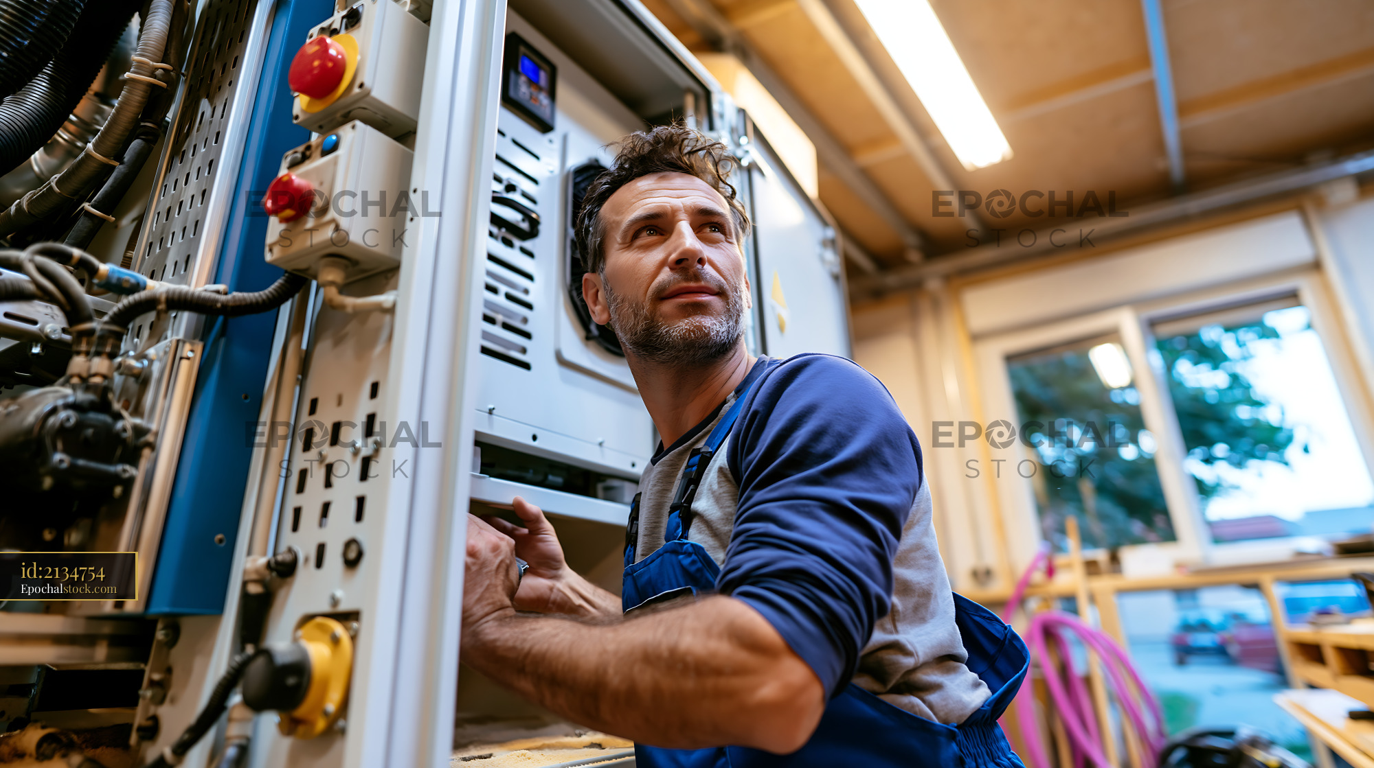 Watermarked full-resolution preview of Man working on machinery in a workshop