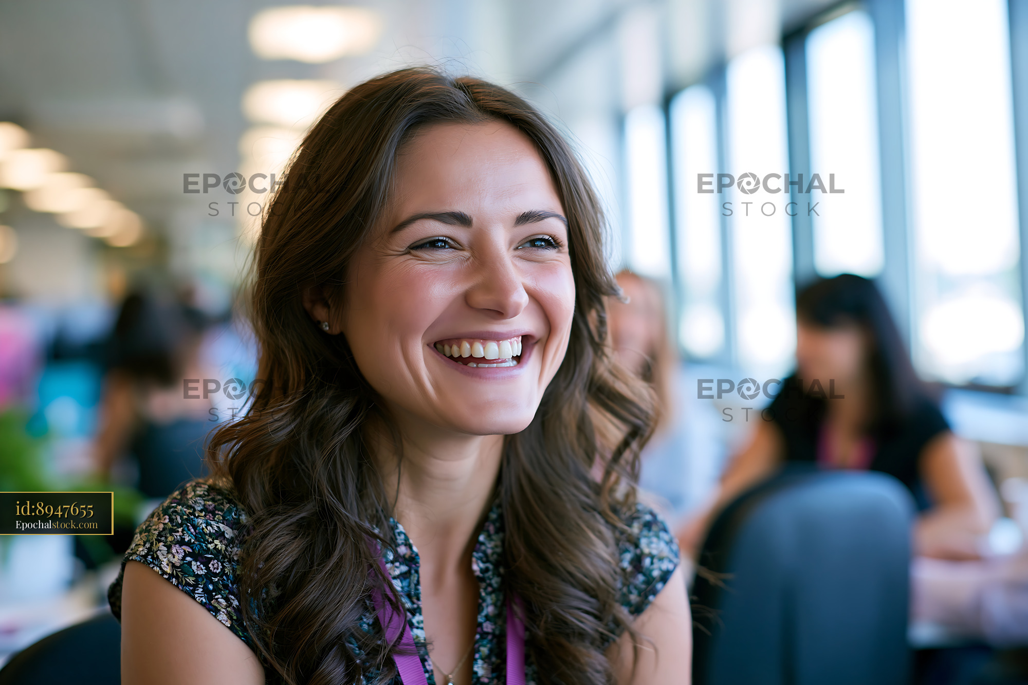 Watermarked full-resolution preview of Woman smiling in a casual indoor setting with people around her