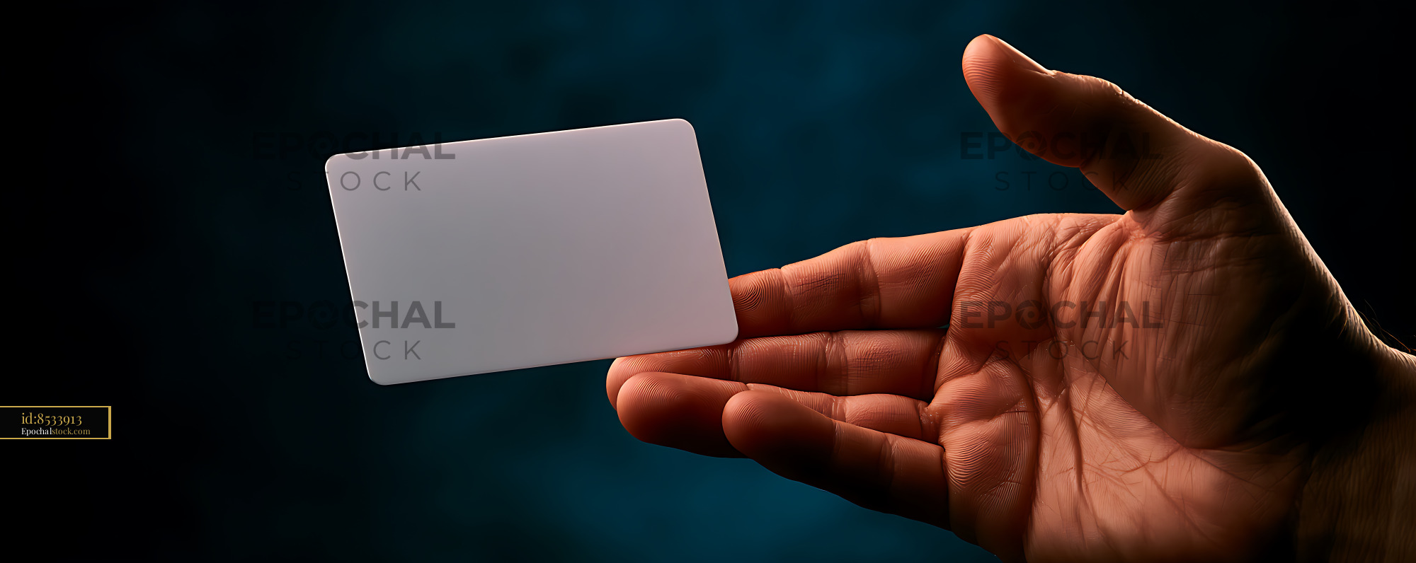 Watermarked full-resolution preview of Close-up hand holding blank white card in dramatic light