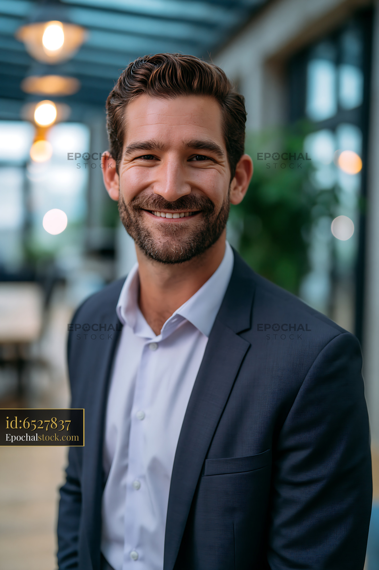 Watermarked full-resolution preview of Smiling man in business suit in modern office setting