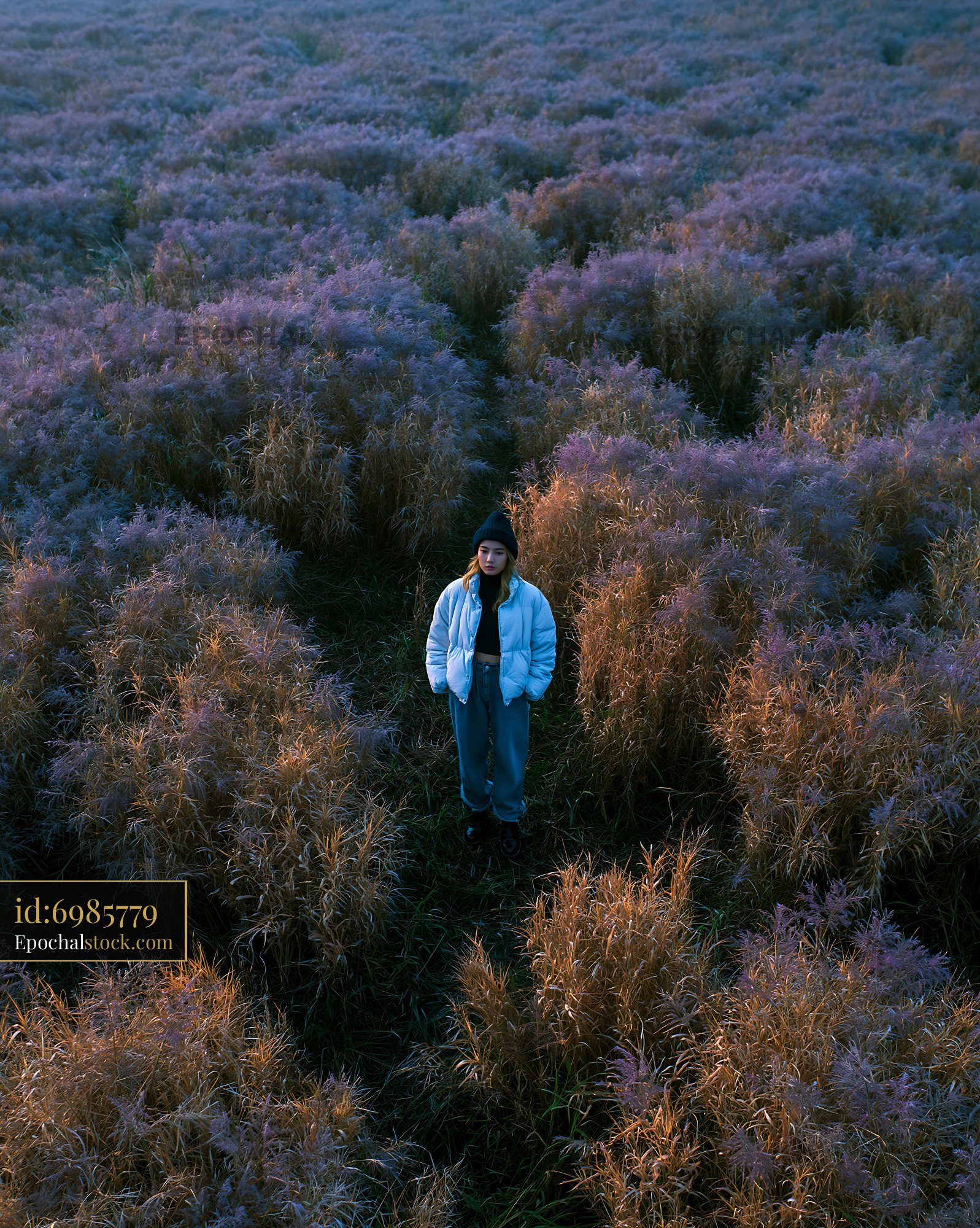 Watermarked full-resolution preview of Person standing in a field of tall grass during daylight