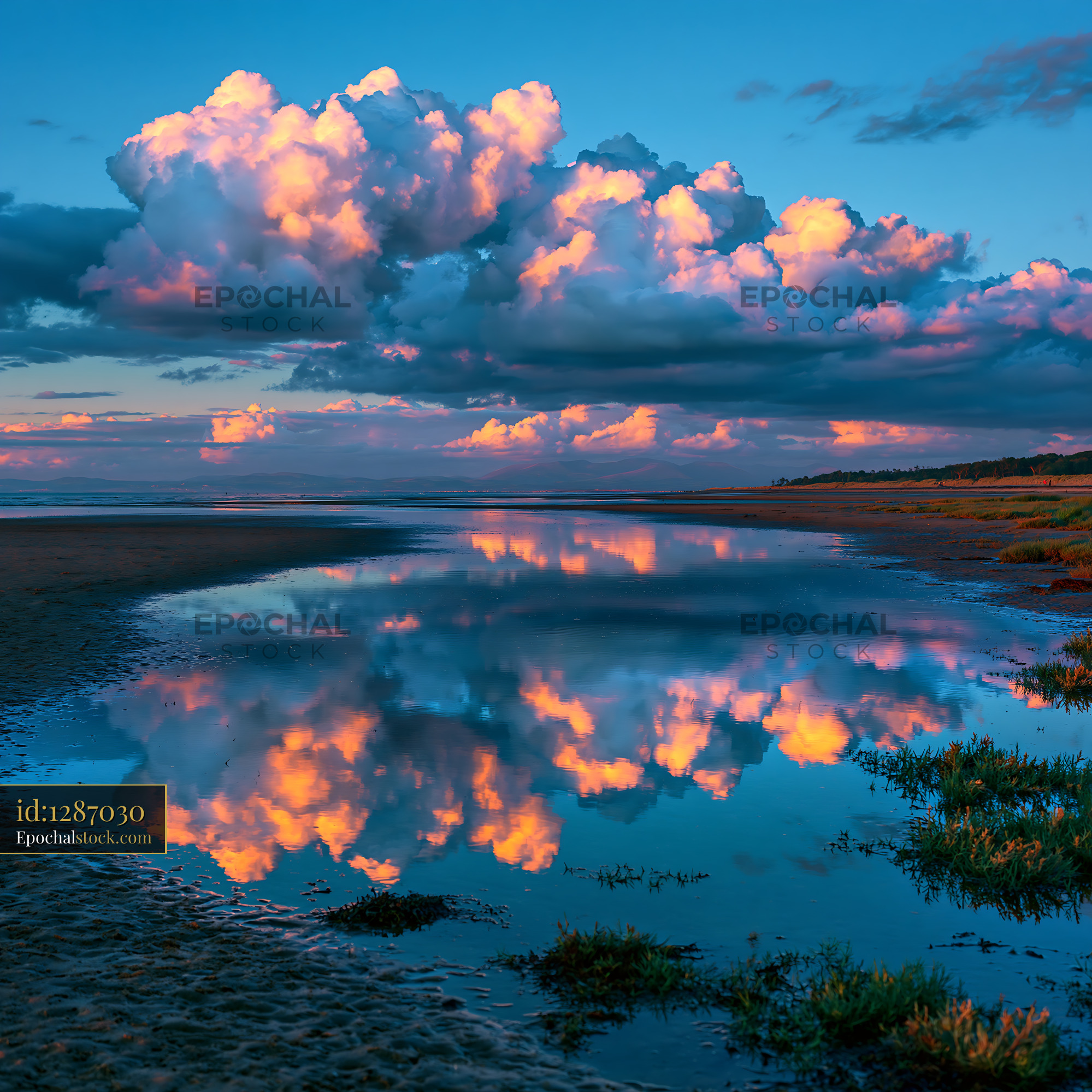 Watermarked full-resolution preview of Colorful clouds reflect in calm water at sunset near the beach