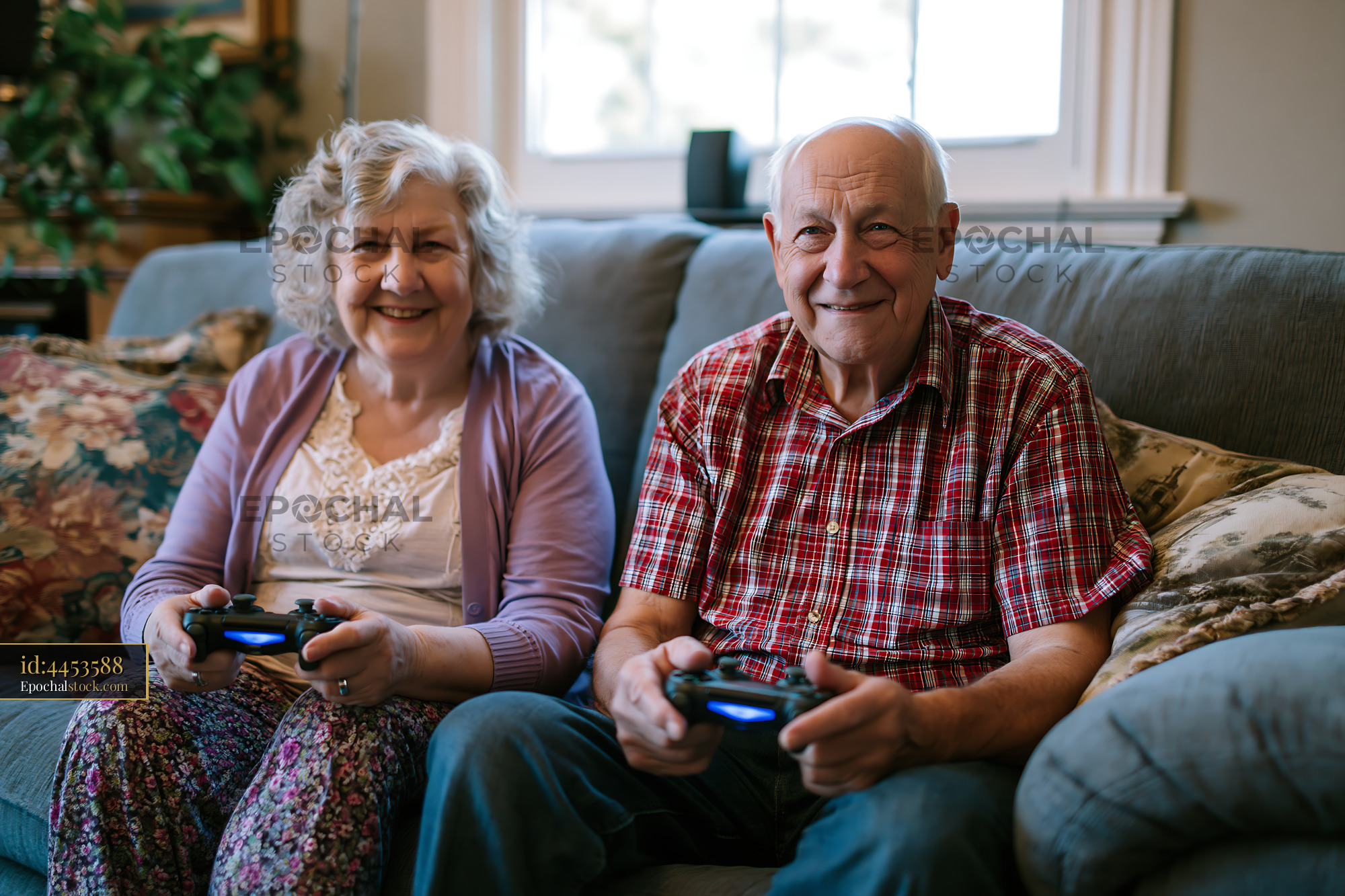 Elderly Couple Playing Video Games on a Couch in Their Home - stock photo