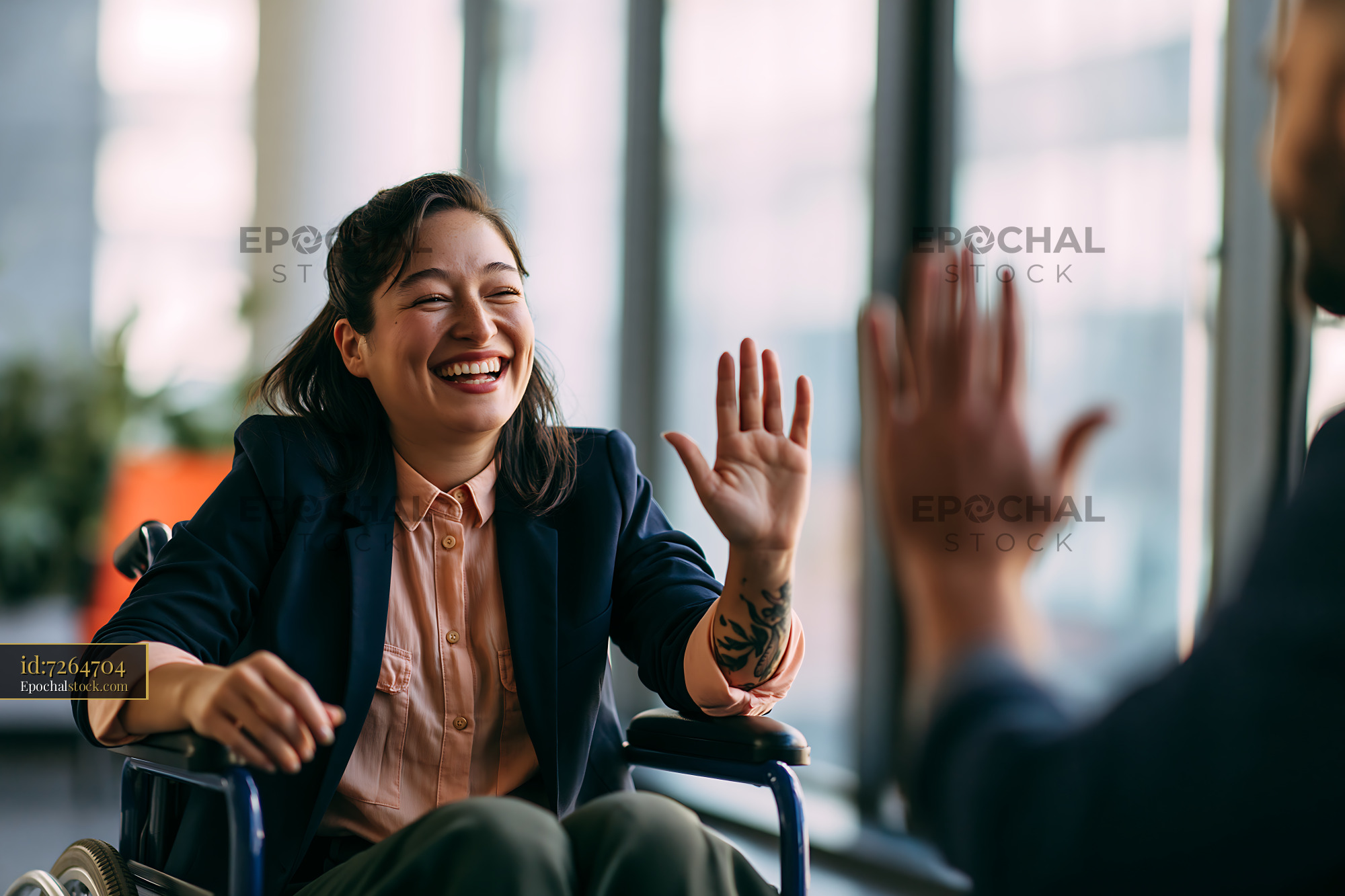 Watermarked full-resolution preview of Woman in wheelchair smiling and waving during conversation indoors