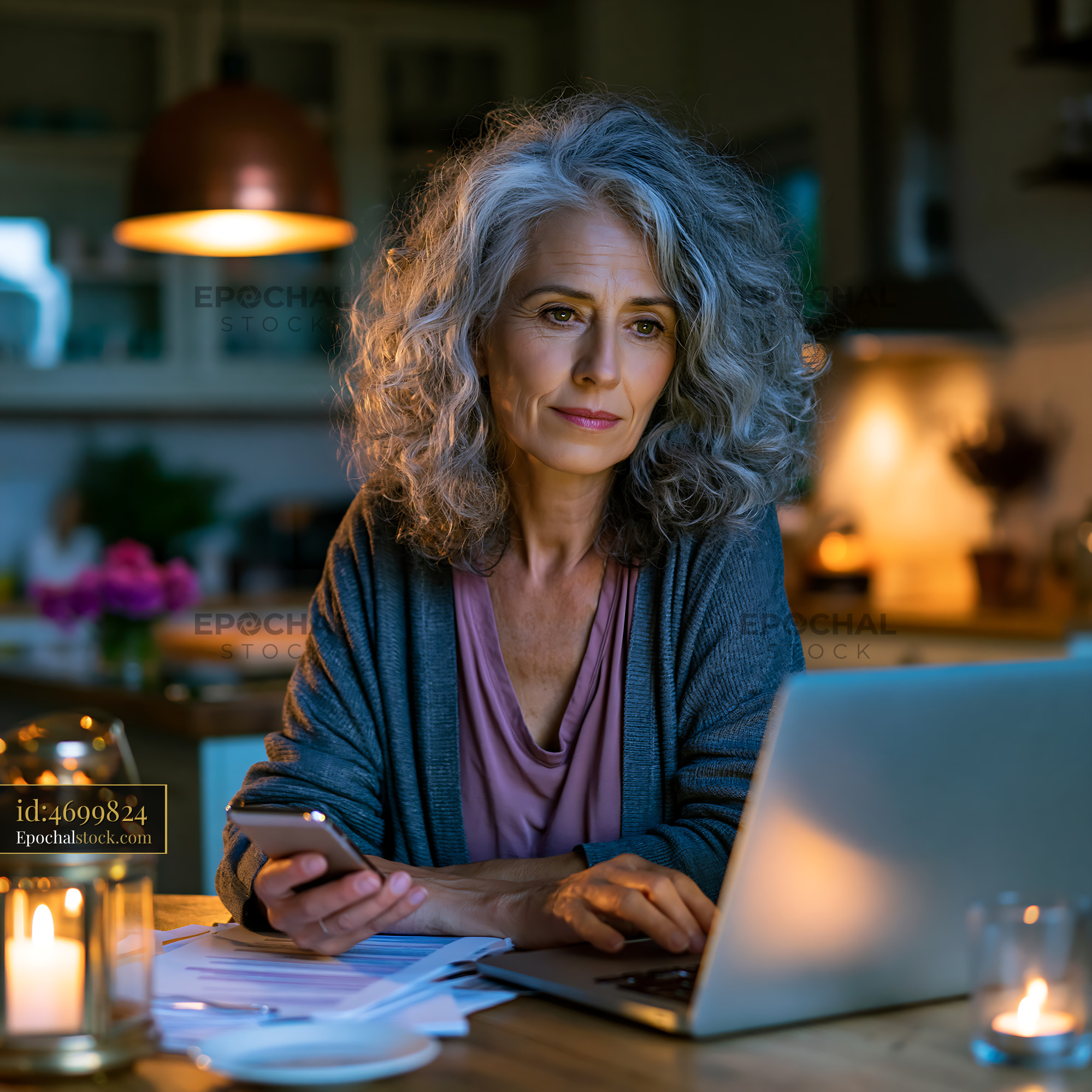 Watermarked full-resolution preview of Woman using a laptop in a dimly lit kitchen
