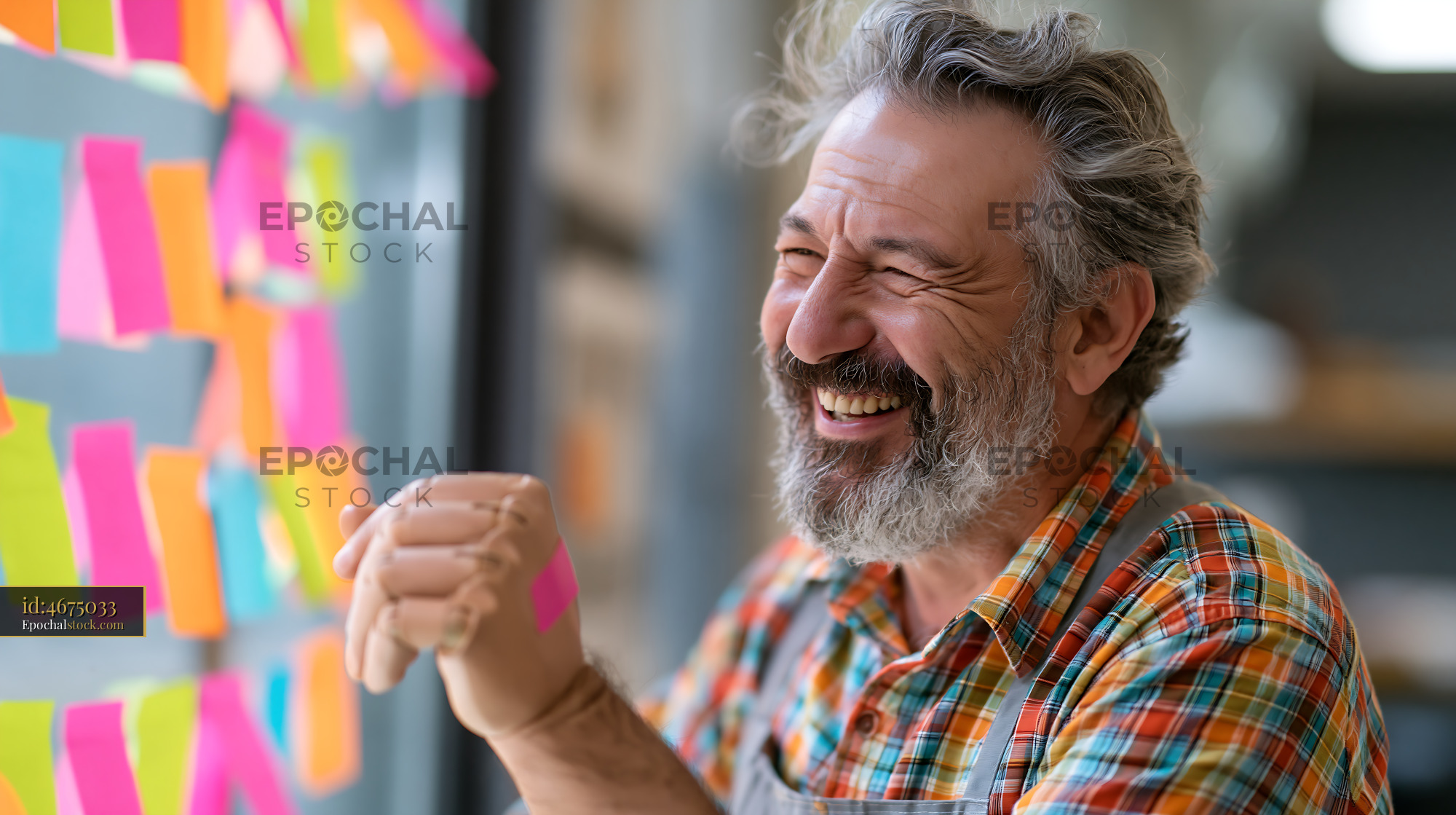 Watermarked full-resolution preview of Man smiling while working with sticky notes in an office