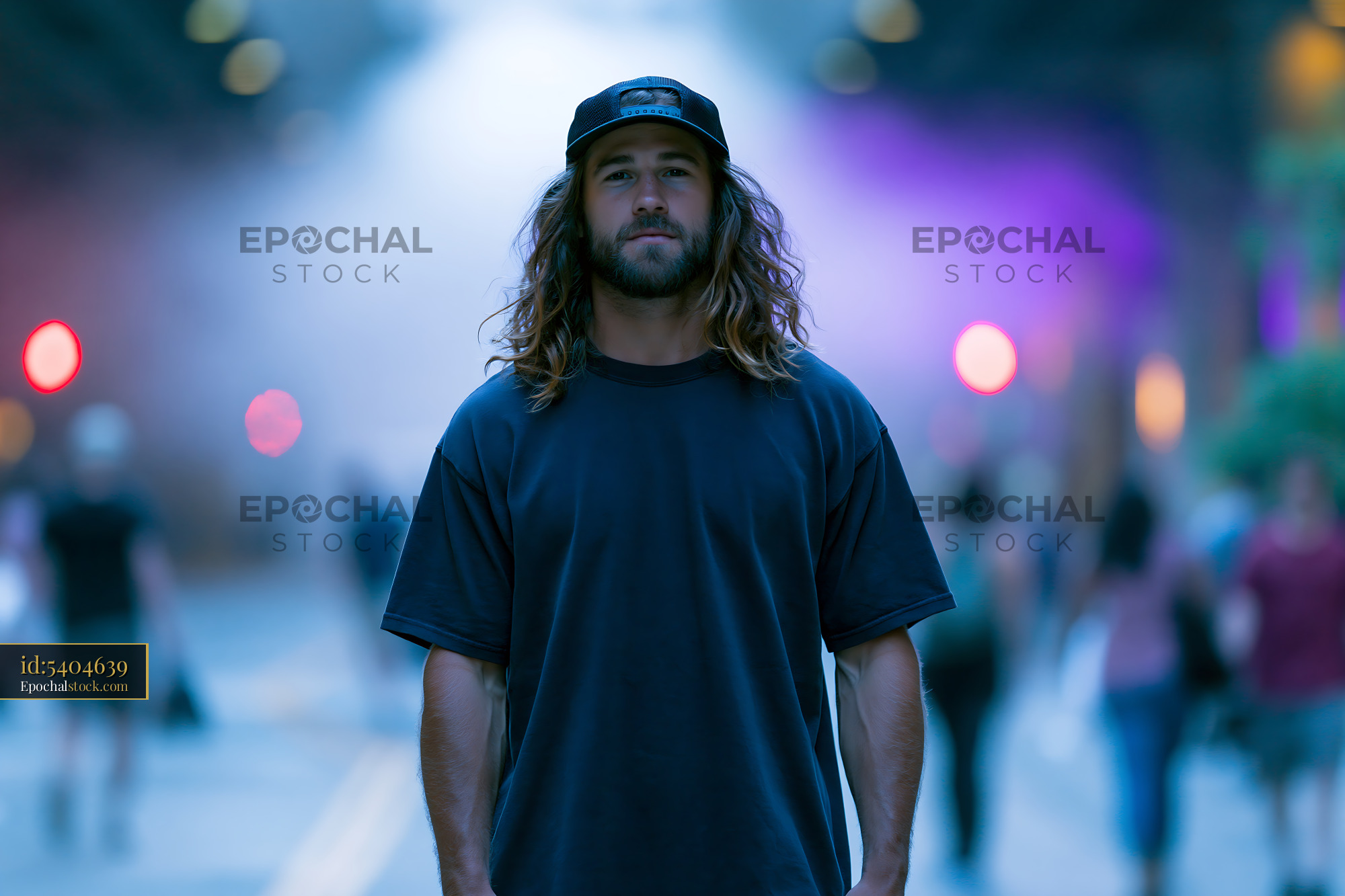 Watermarked full-resolution preview of Man stands on street with people walking in the background at night