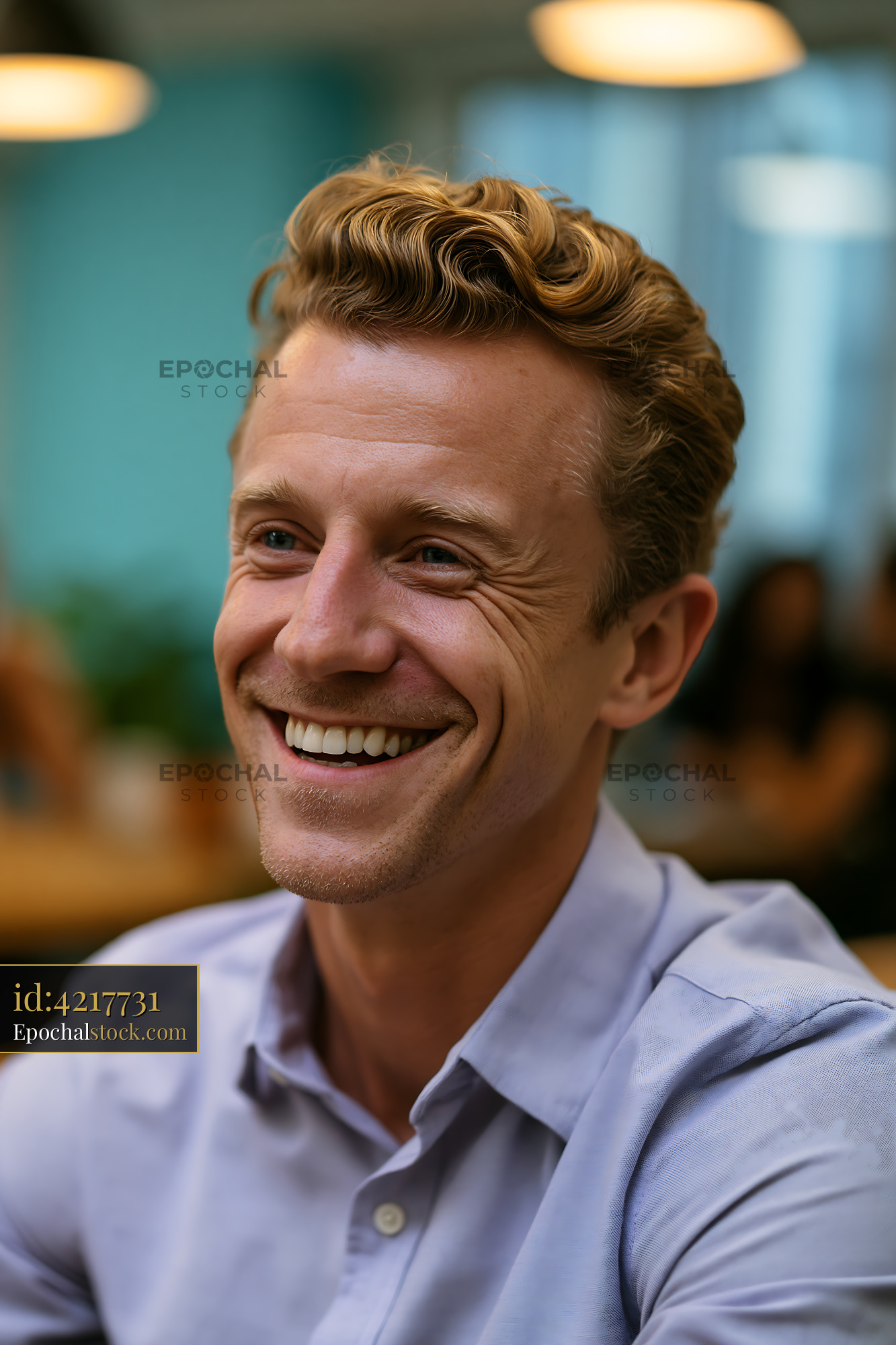 Watermarked full-resolution preview of Smiling man with curly hair sitting in a café