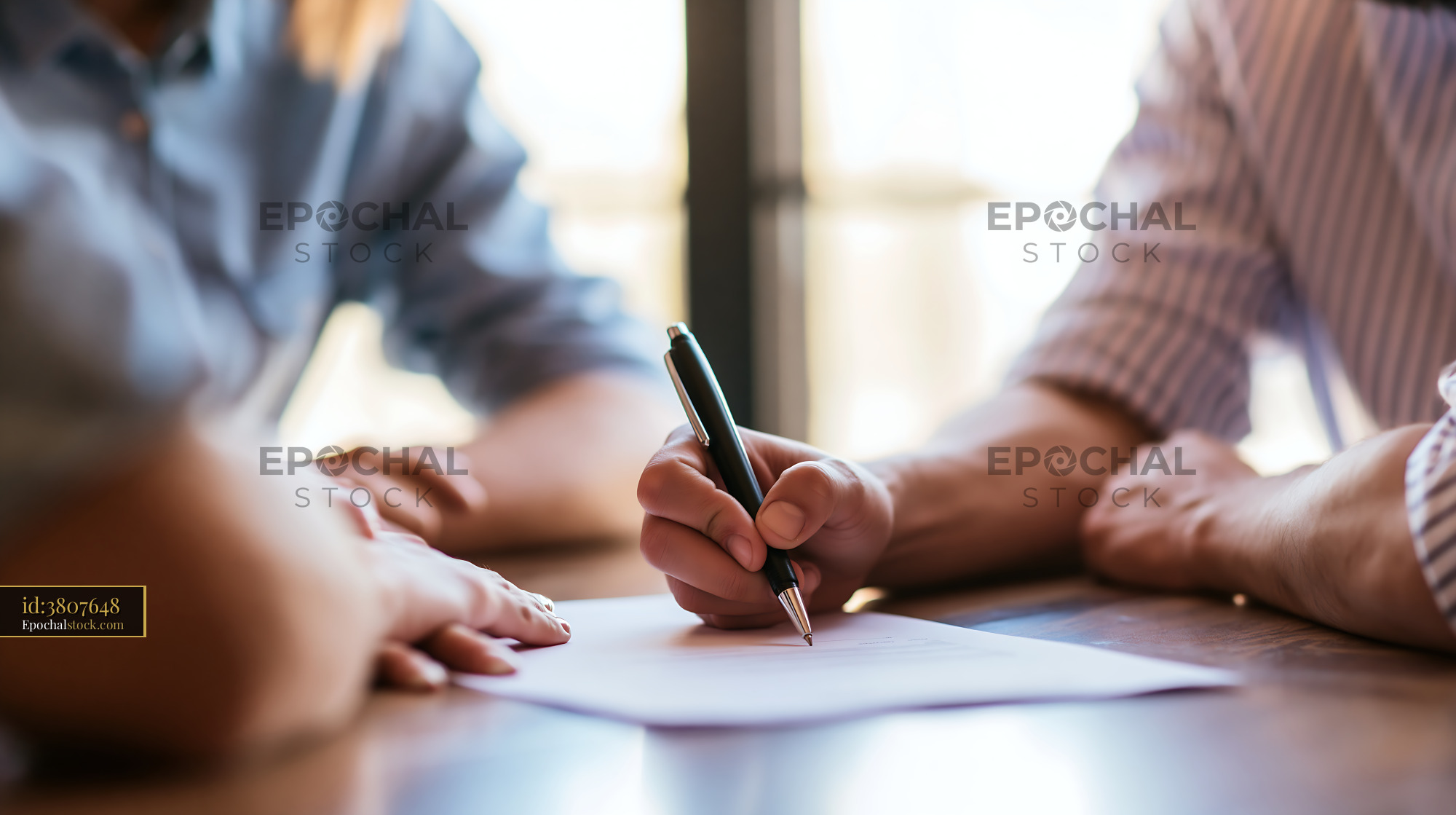Watermarked full-resolution preview of Group of people signing a document at a table in an office setting