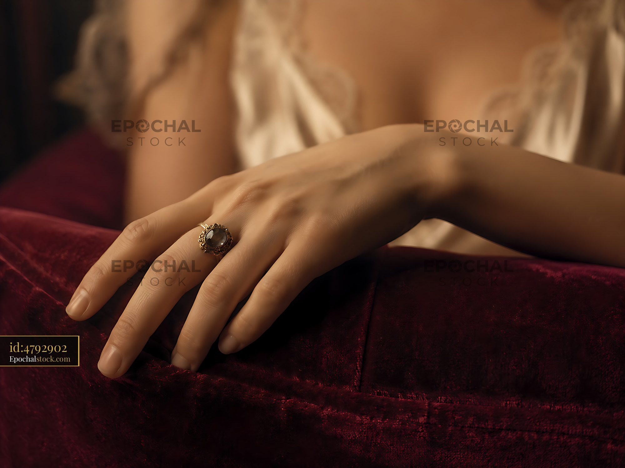 Watermarked full-resolution preview of Close-up of a hand with a ring resting on plush fabric
