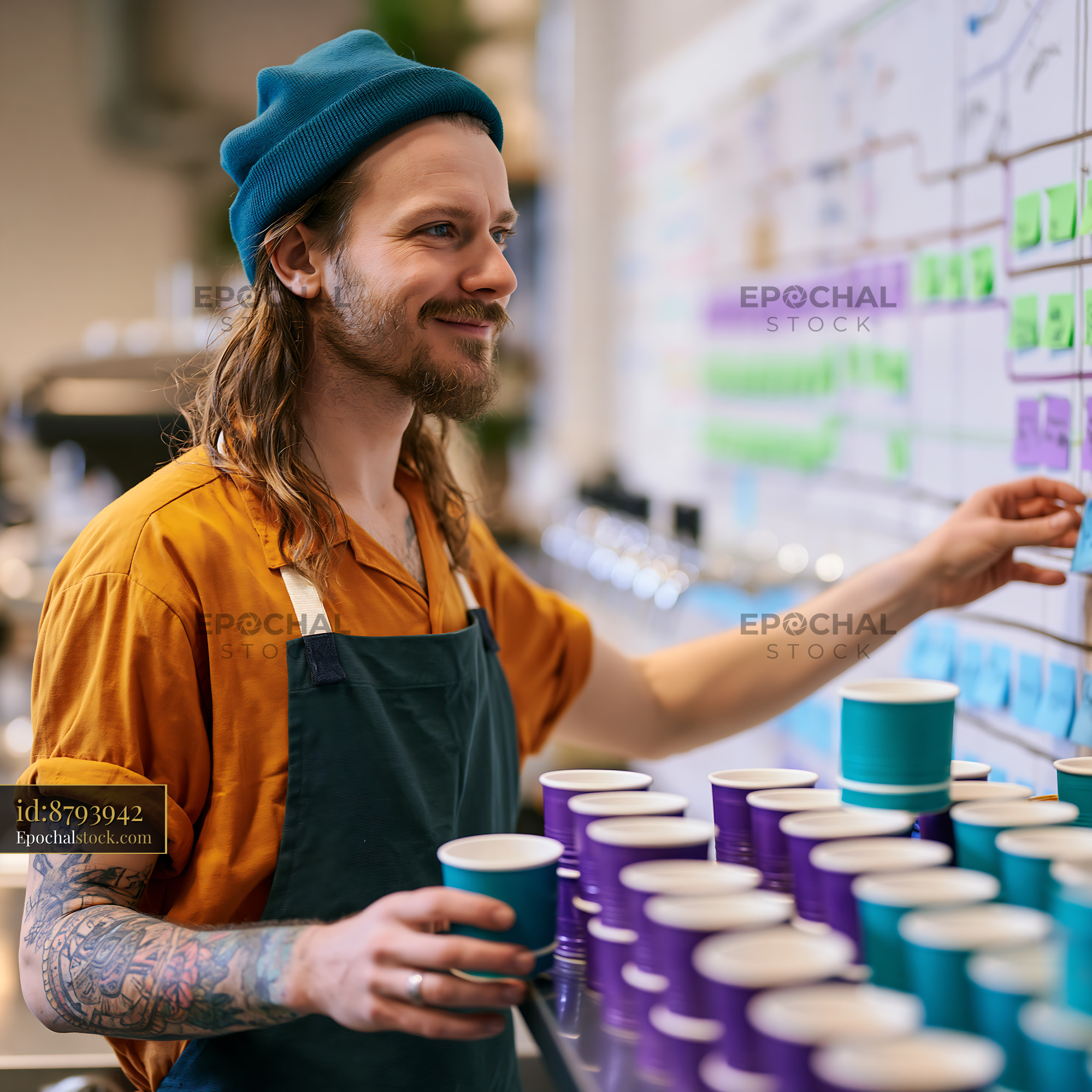 Watermarked full-resolution preview of Young man working at a coffee shop making drinks