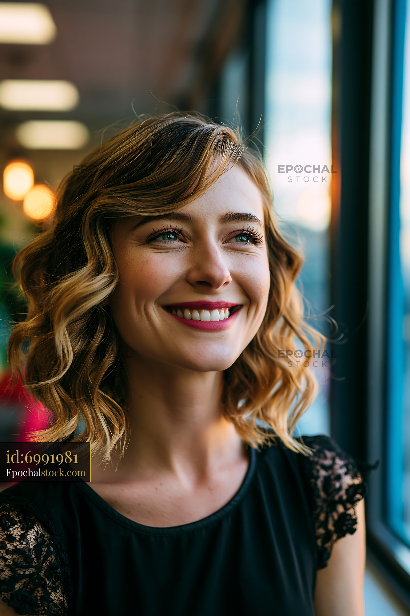 Woman Smiling While Looking out of a Window During Sunset - stock photo