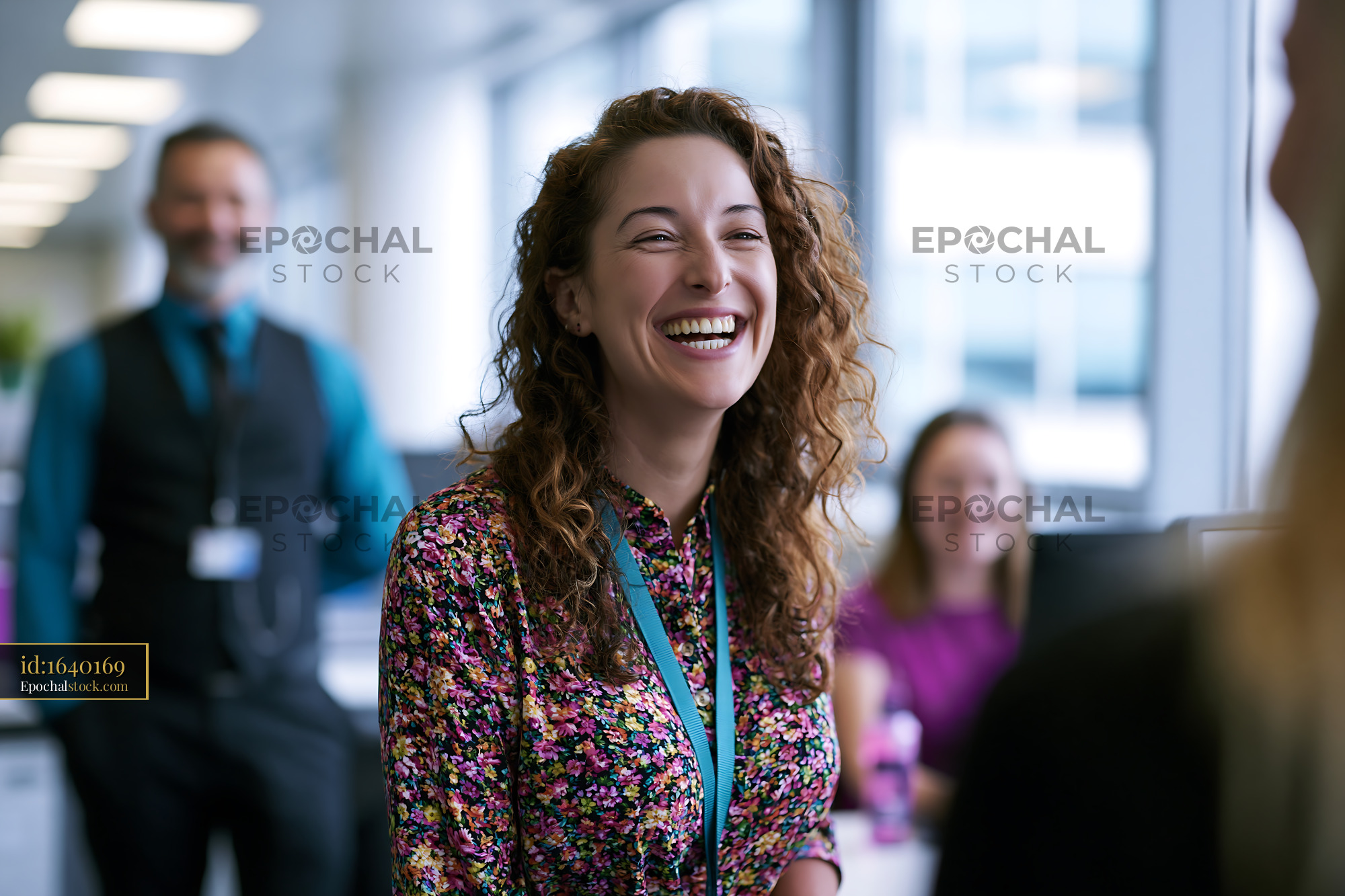 Watermarked full-resolution preview of Woman smiling in office during conversation with coworkers