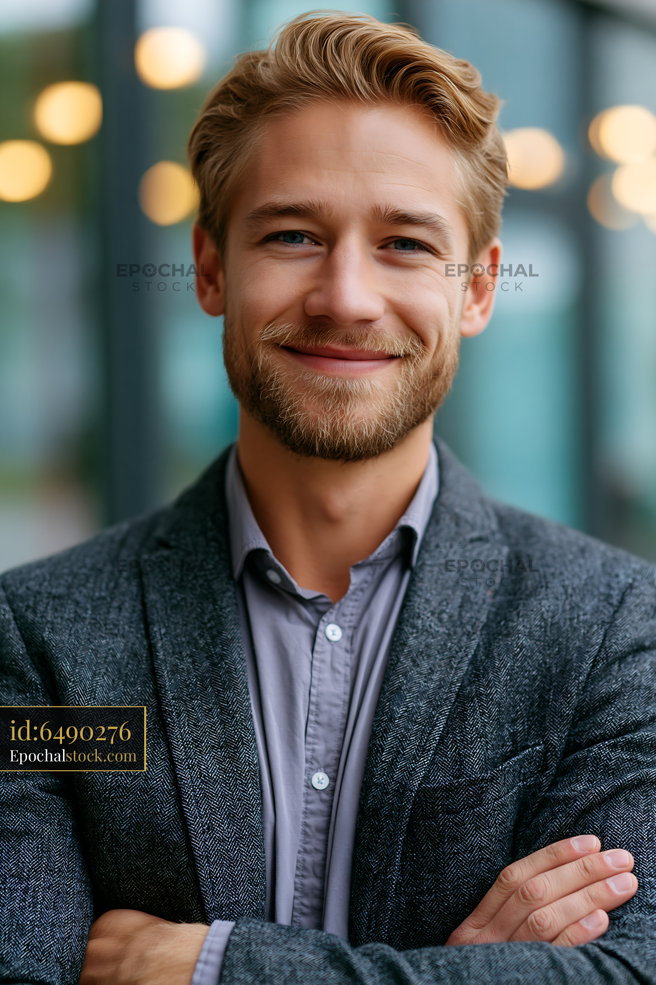 Watermarked full-resolution preview of Smiling man in a gray blazer with crossed arms