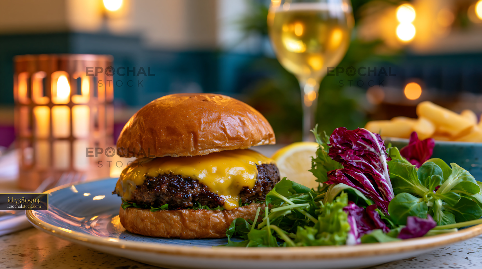 Watermarked full-resolution preview of Delicious burger served with salad and fries in a restaurant