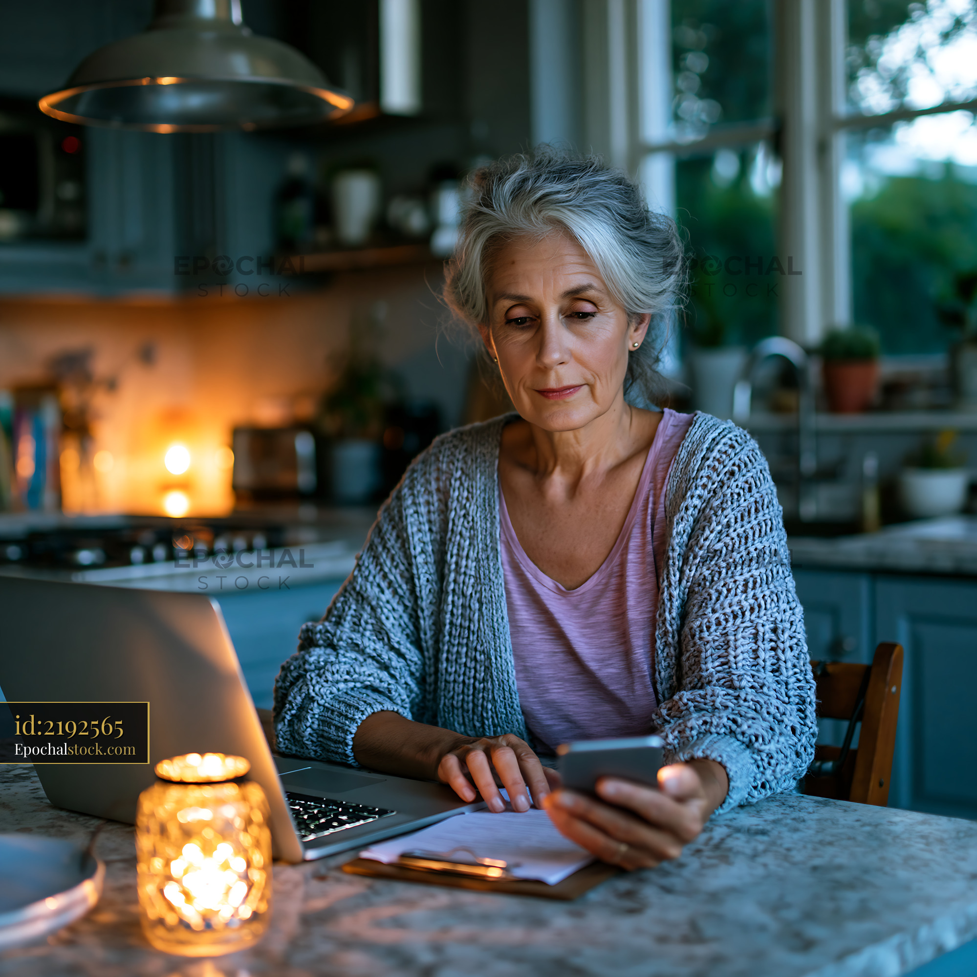 Watermarked full-resolution preview of Woman using smartphone at kitchen table during evening