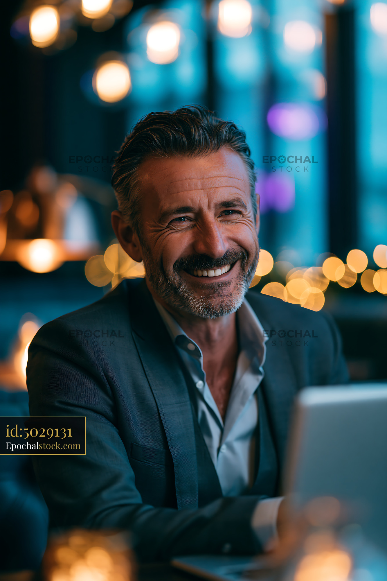 Watermarked full-resolution preview of Businessman smiles at desk in modern office space