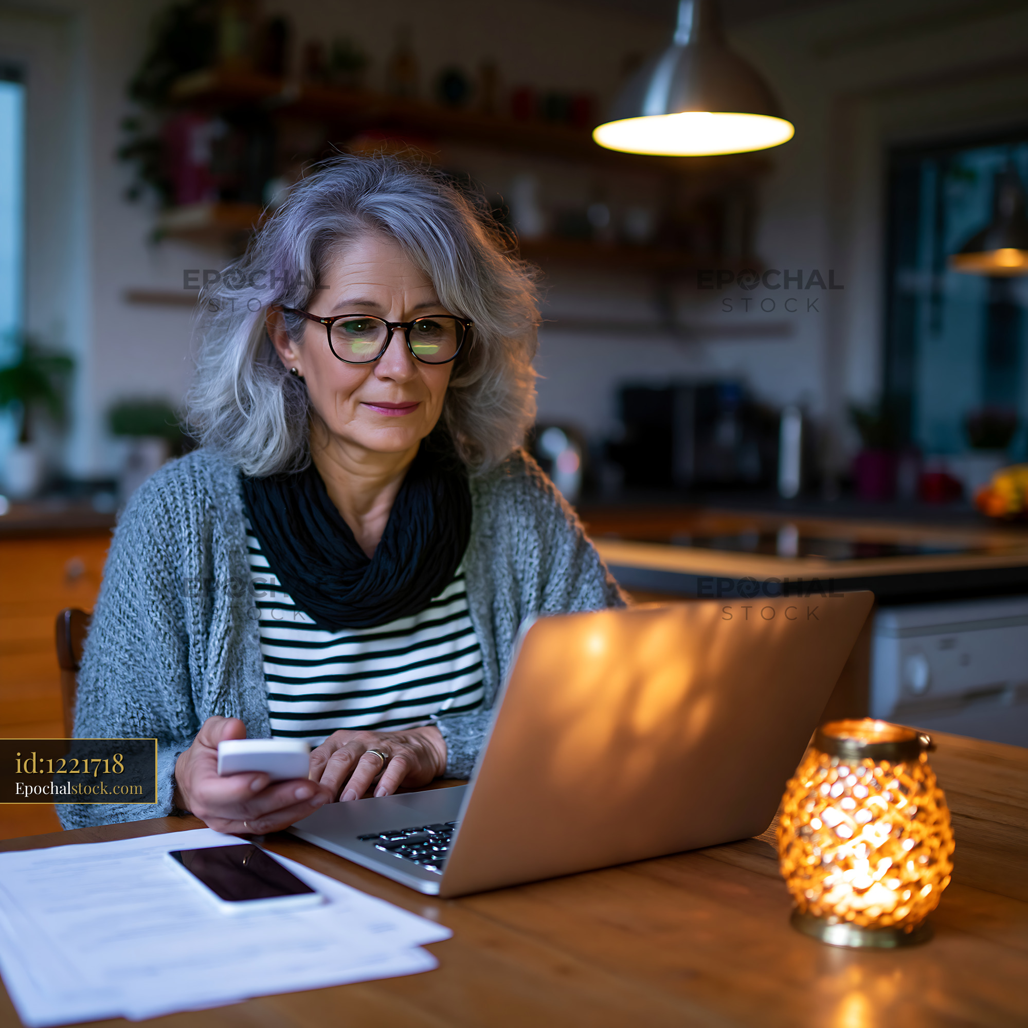 Watermarked full-resolution preview of Woman using laptop at home in evening