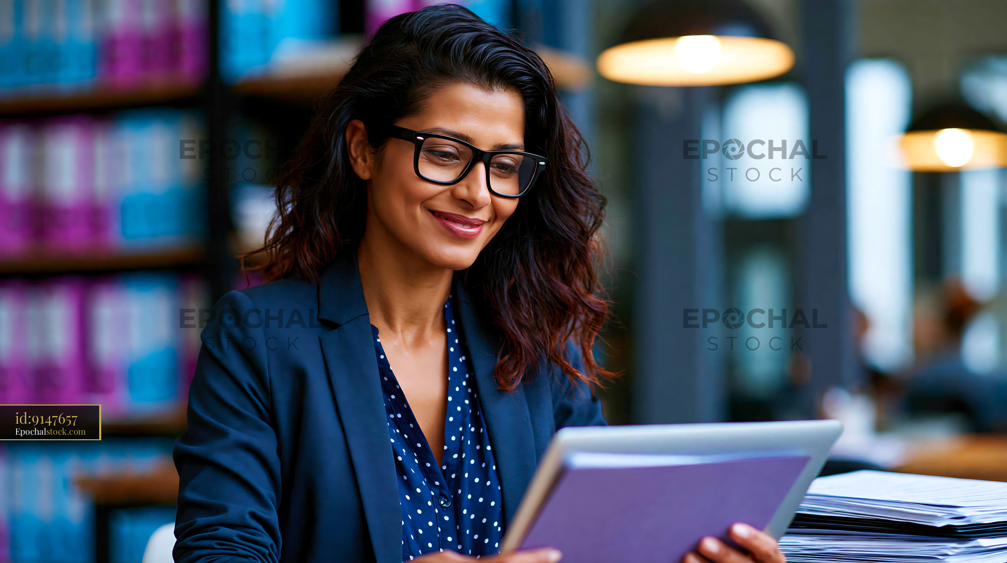 Watermarked full-resolution preview of Woman using tablet in modern library setting