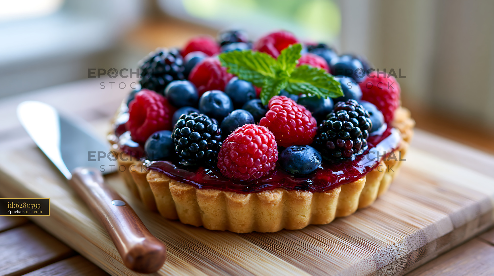 Watermarked full-resolution preview of Berry tart on wooden board with knife and fresh mint leaf