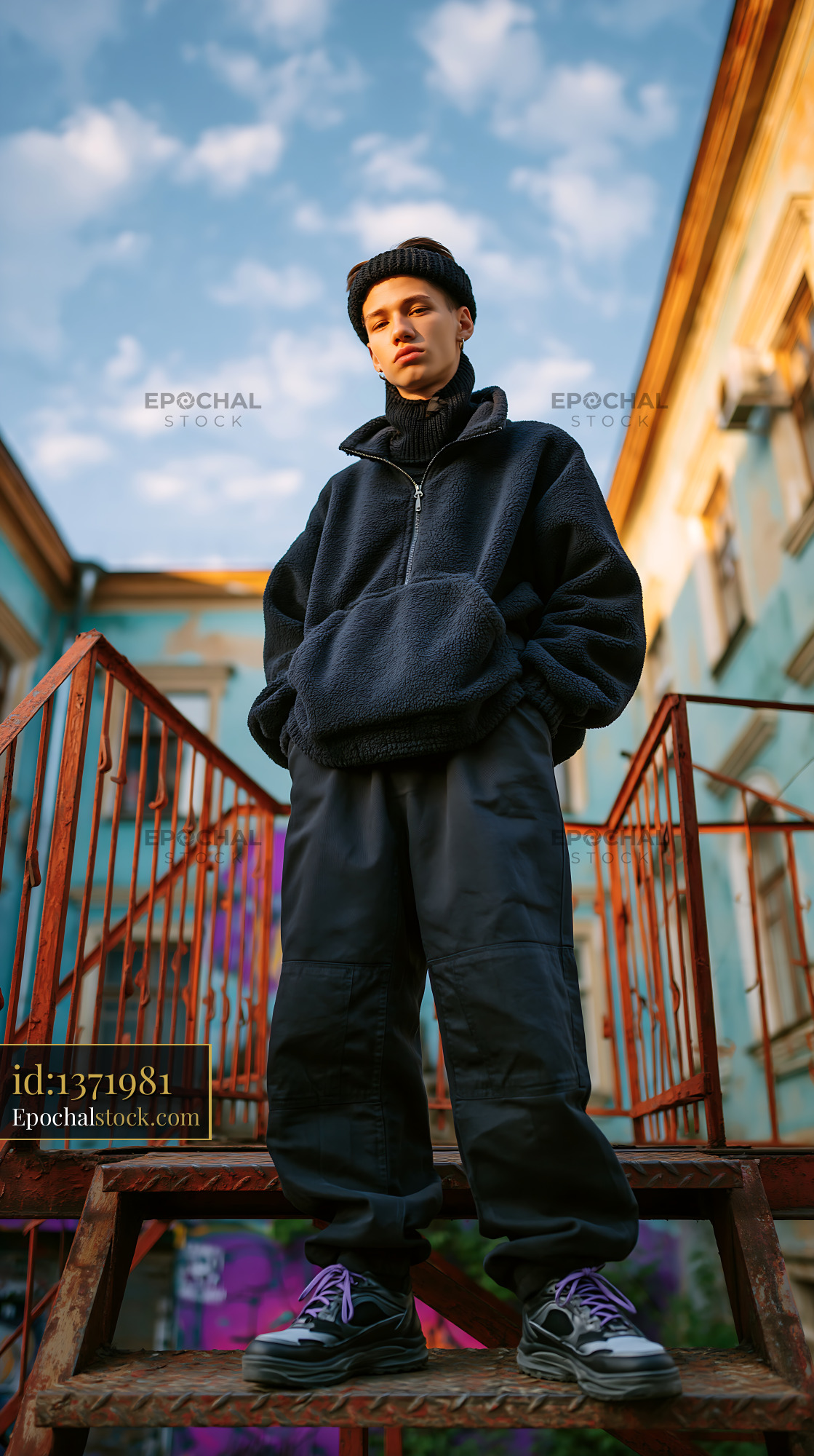 Young Man in Knitted Balaclava Standing on Stairs, City Setting - stock photo