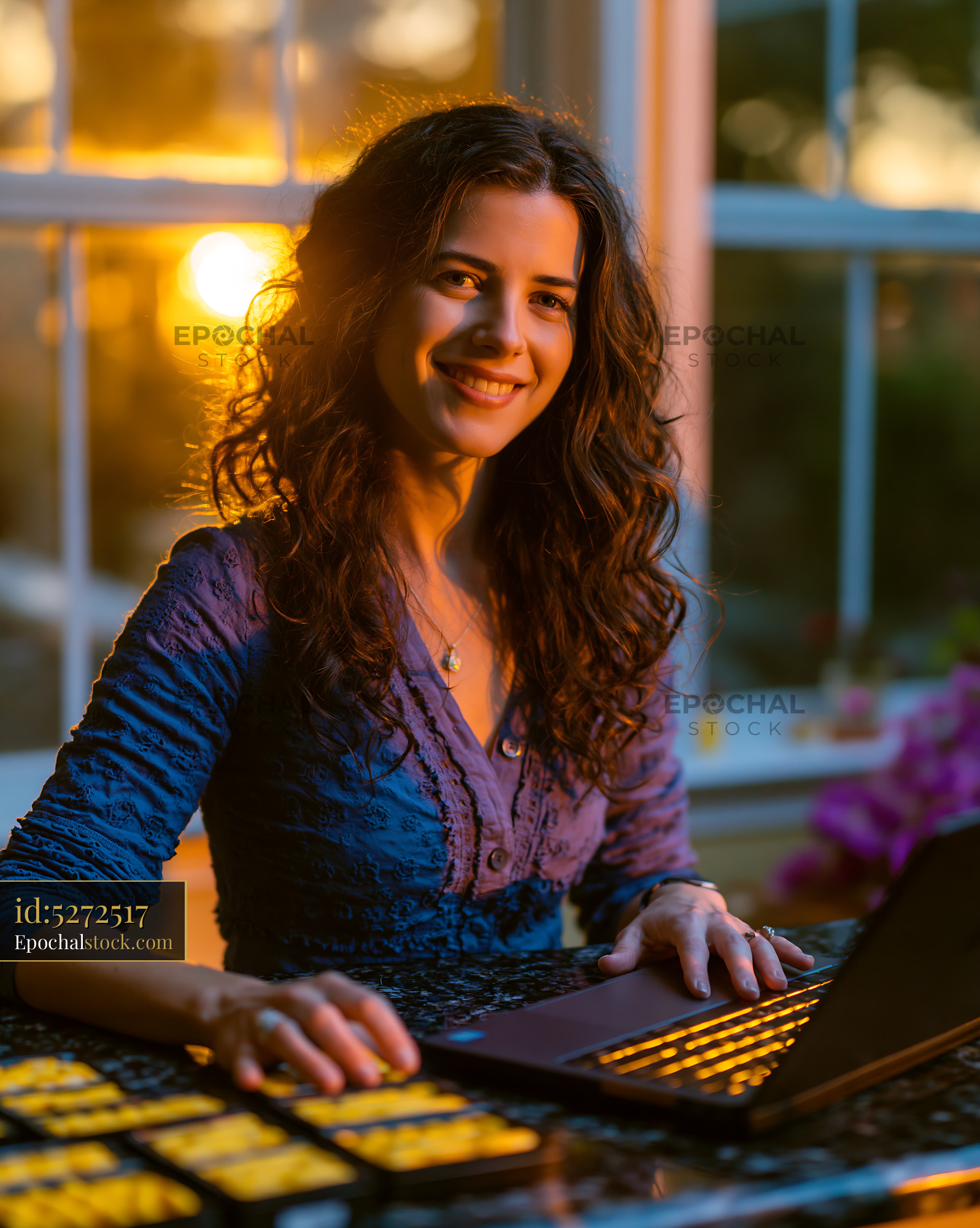 Watermarked full-resolution preview of Woman working on laptop during sunset at home