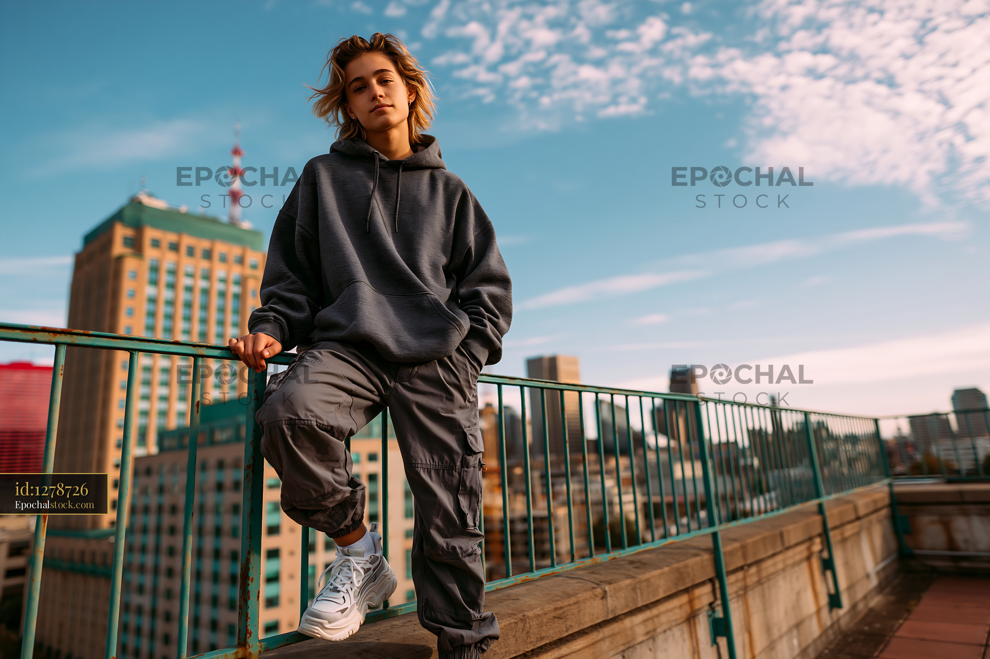 Watermarked full-resolution preview of Young person standing on a rooftop with city skyline in the background