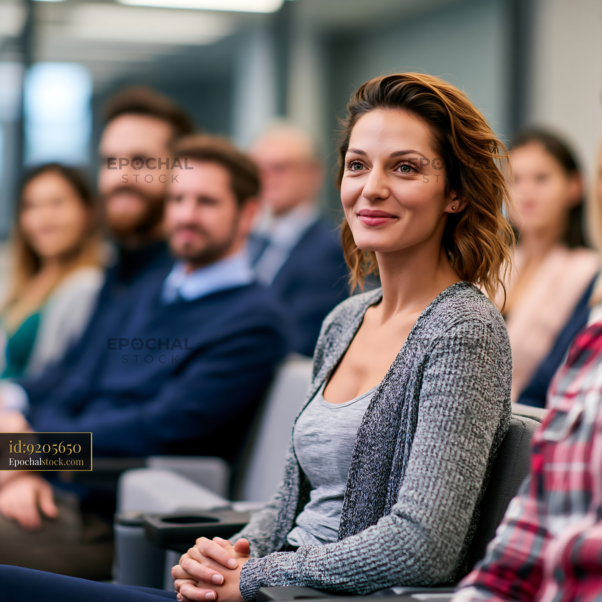 Watermarked full-resolution preview of Smiling woman sitting in an indoor audience