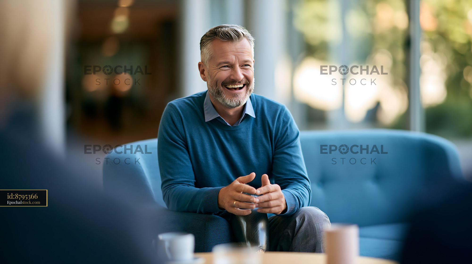 Watermarked full-resolution preview of Man laughs during discussion in a modern office setting