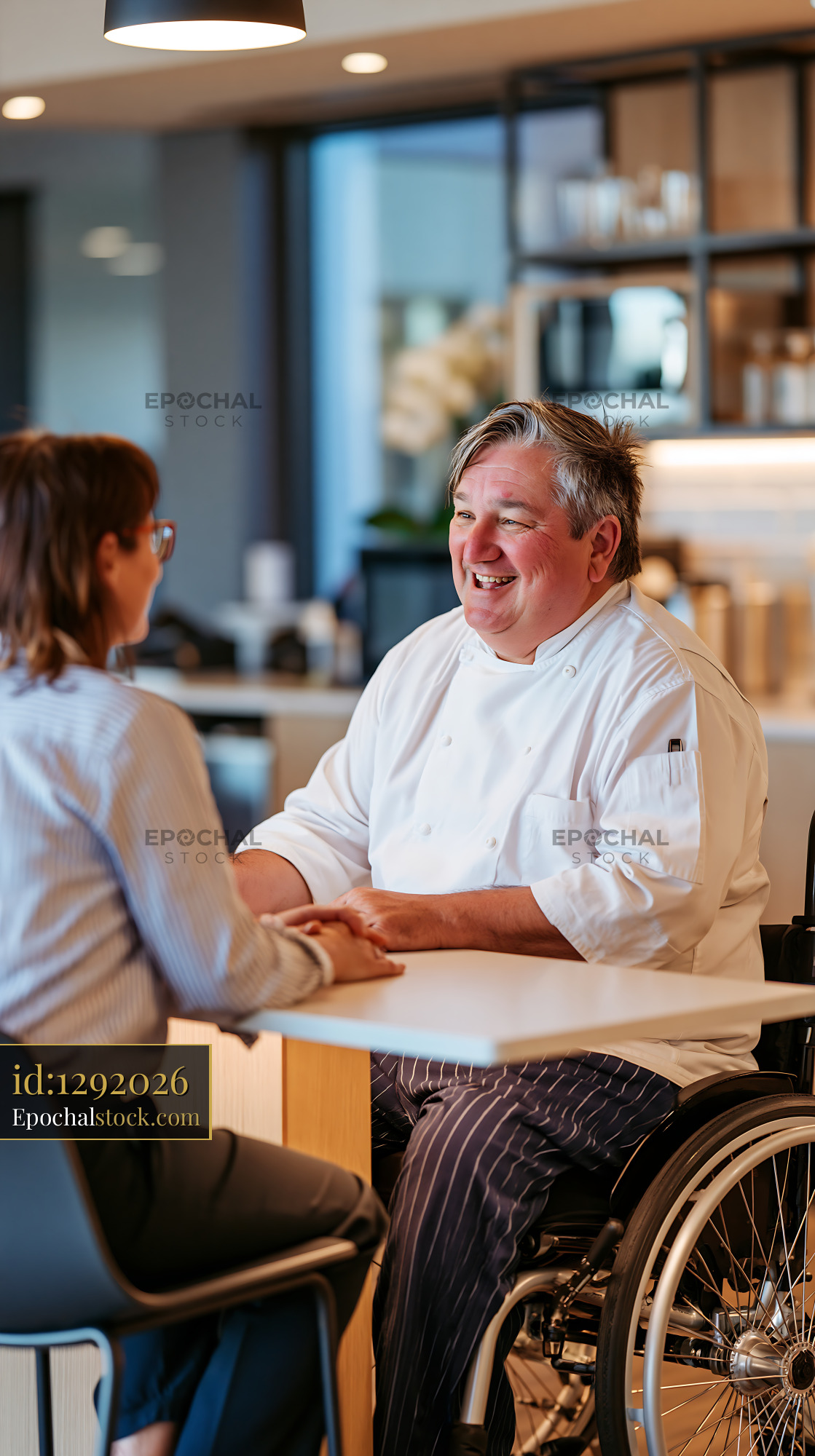 Watermarked full-resolution preview of Smiling chef talking with customer at restaurant table
