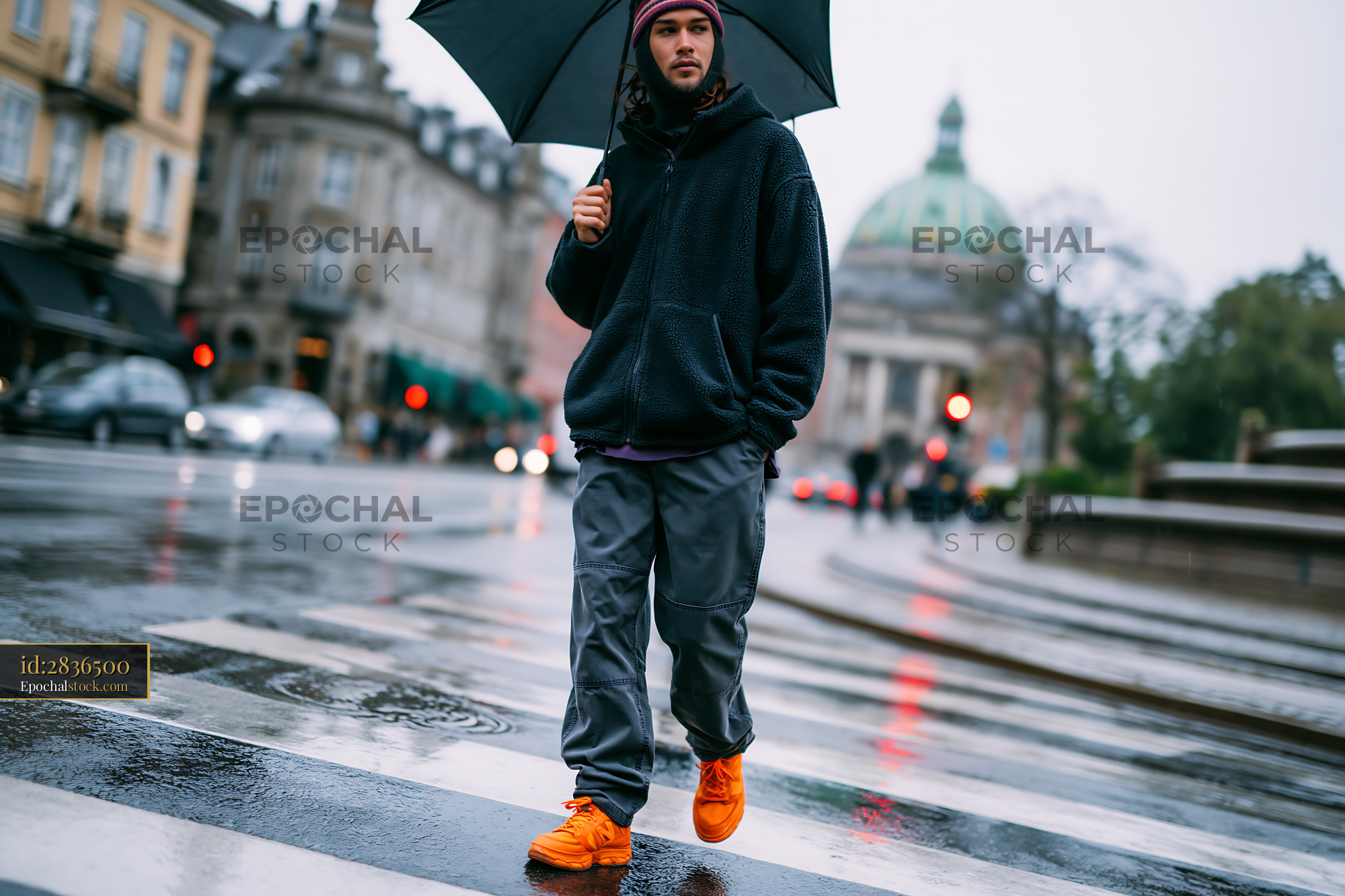 Watermarked full-resolution preview of Person crossing a wet street under an umbrella