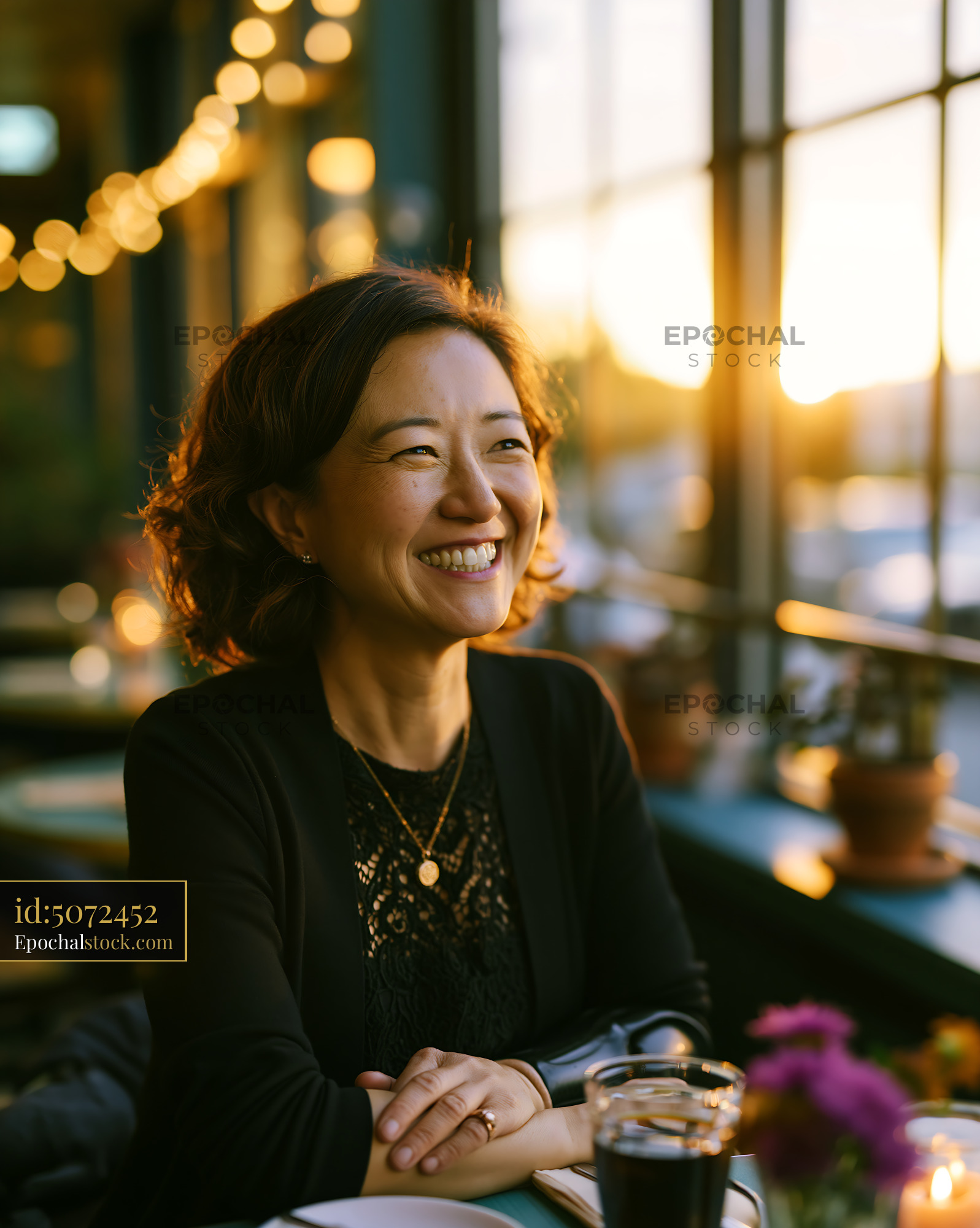 Watermarked full-resolution preview of Happy woman seated in a warmly lit cafe