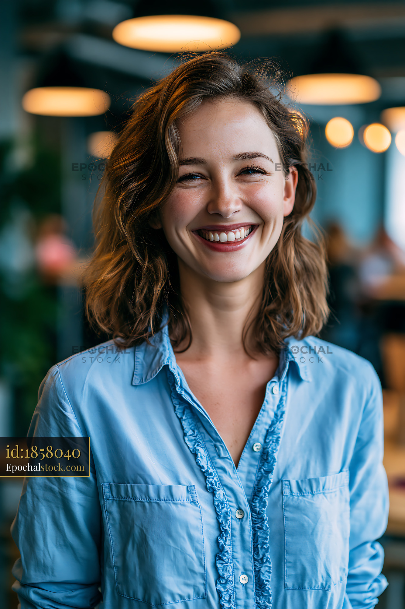Watermarked full-resolution preview of Smiling woman in blue shirt at modern cafe