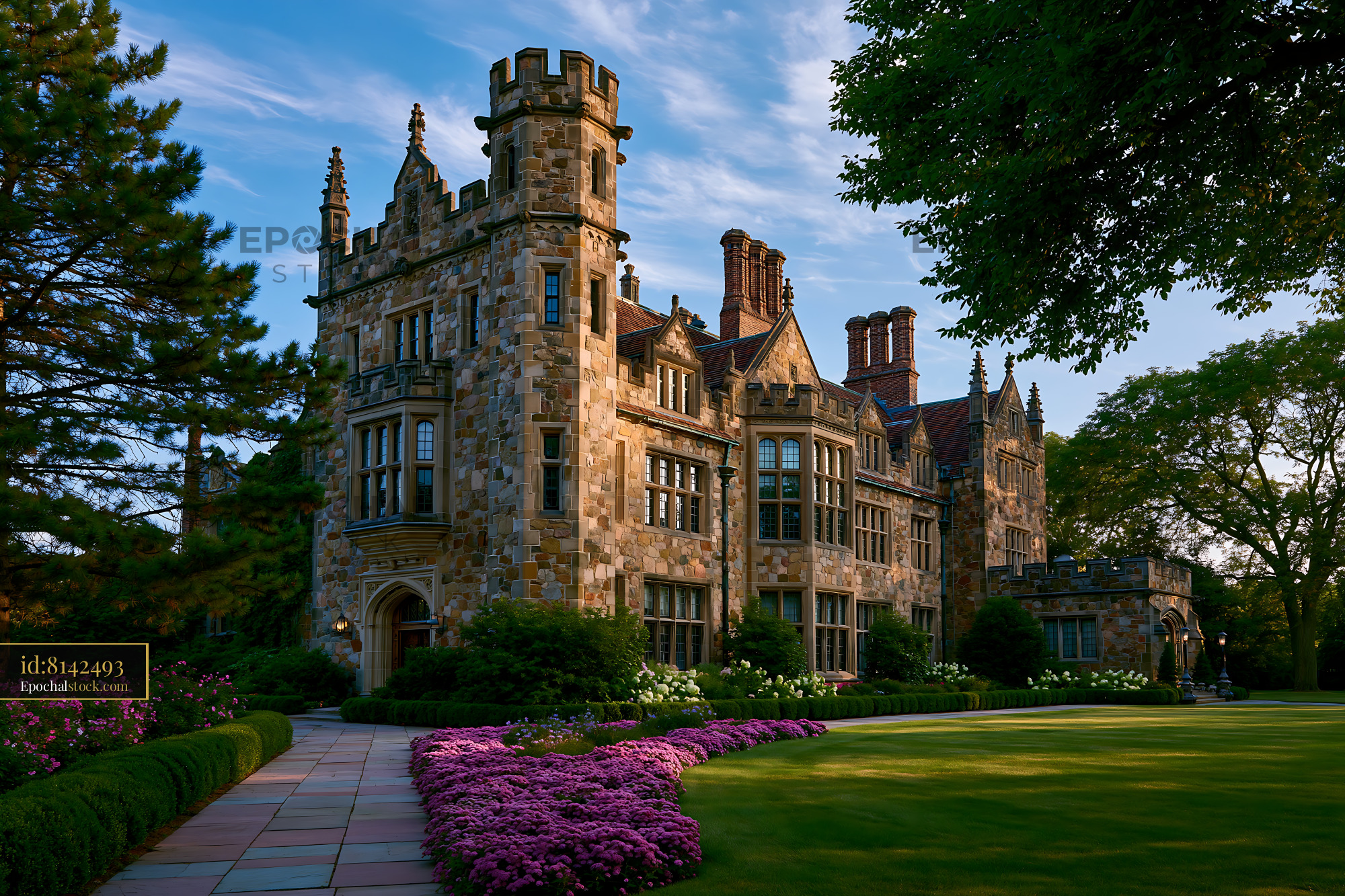 Watermarked full-resolution preview of Historic stone mansion with lush garden in bright sunlight