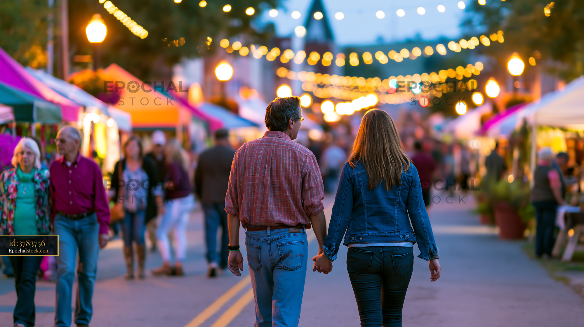 Watermarked full-resolution preview of Couple walking hand in hand at an outdoor market in the evening