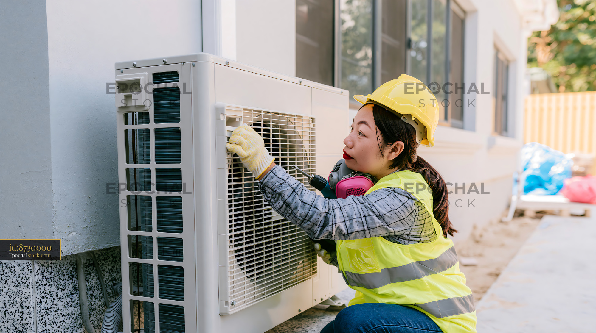 Watermarked full-resolution preview of Woman adjusting air conditioning unit during construction work