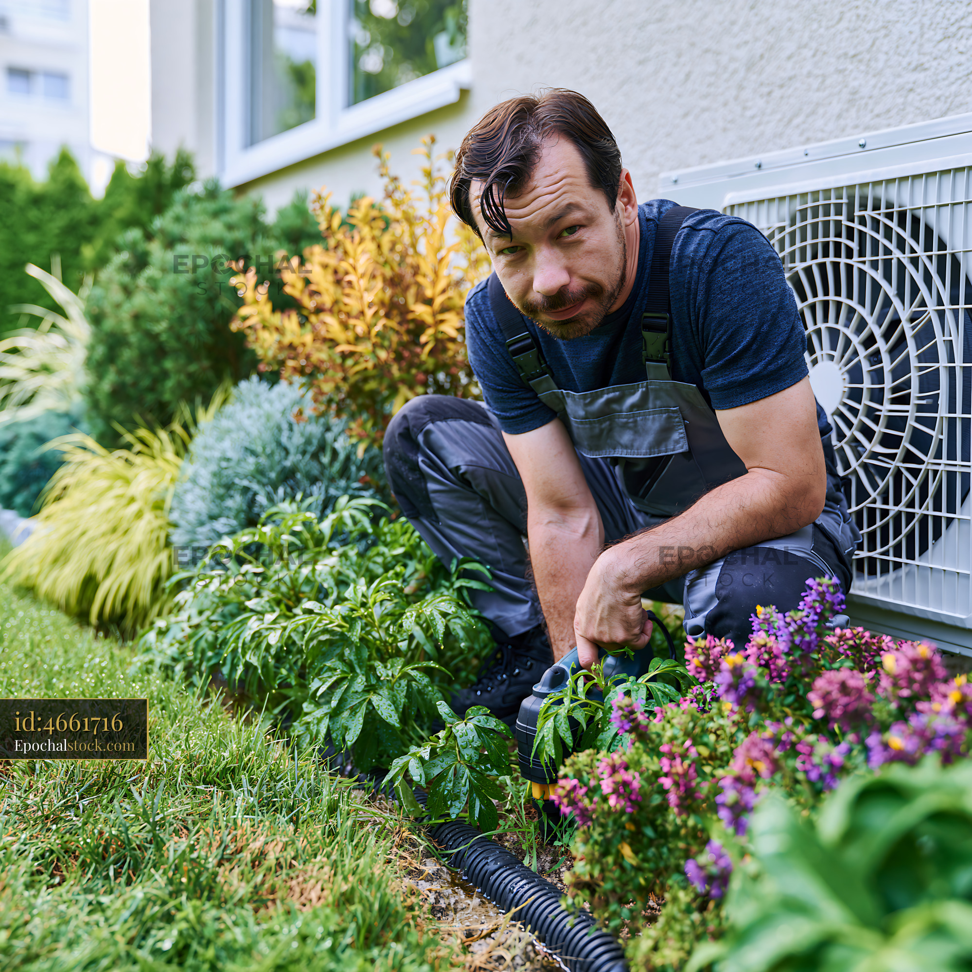 Watermarked full-resolution preview of Gardener trimming plants near an air conditioning unit