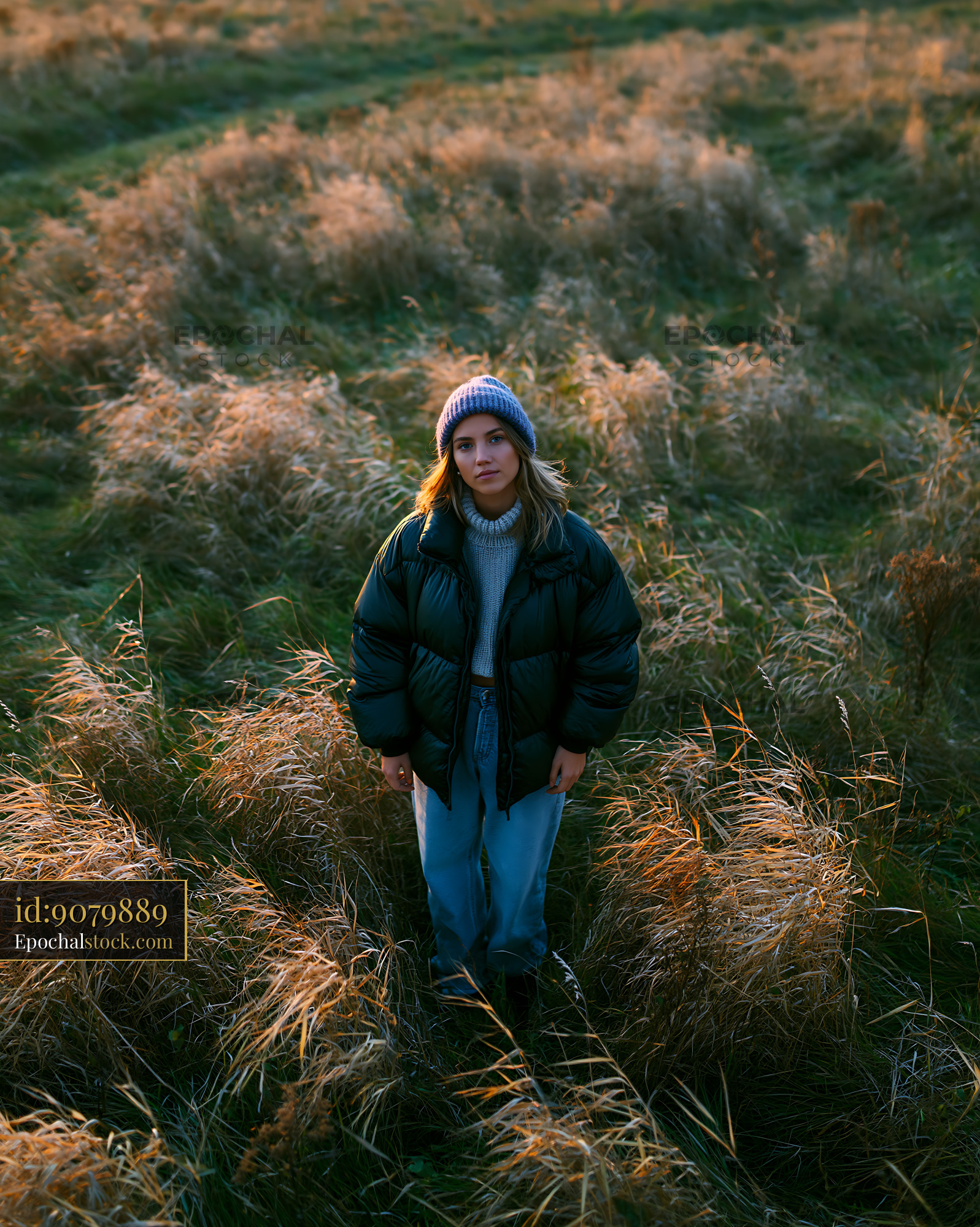 Watermarked full-resolution preview of Woman standing in a field of grass during sunset