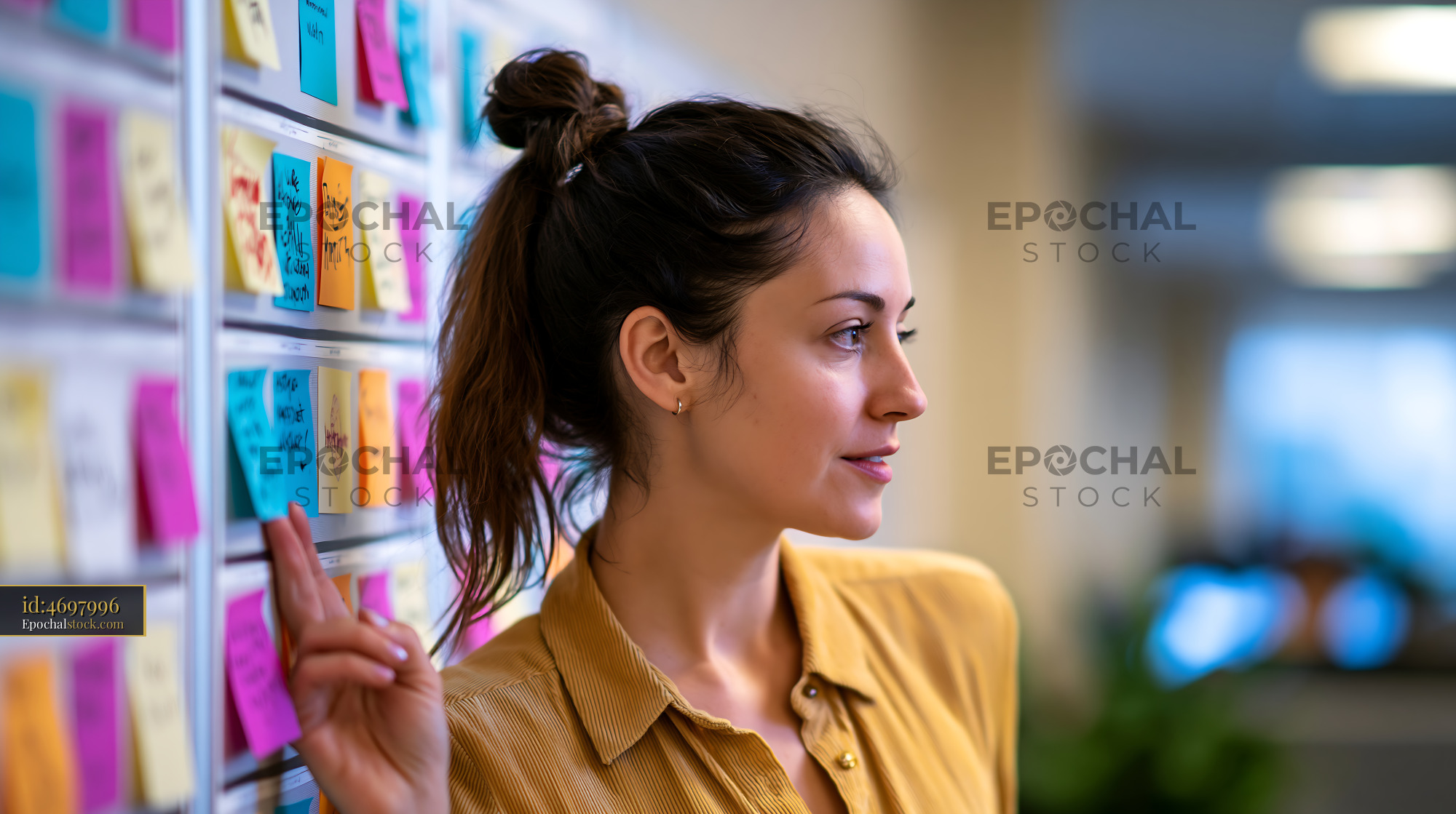 Watermarked full-resolution preview of Woman standing near a wall covered with sticky notes in an office